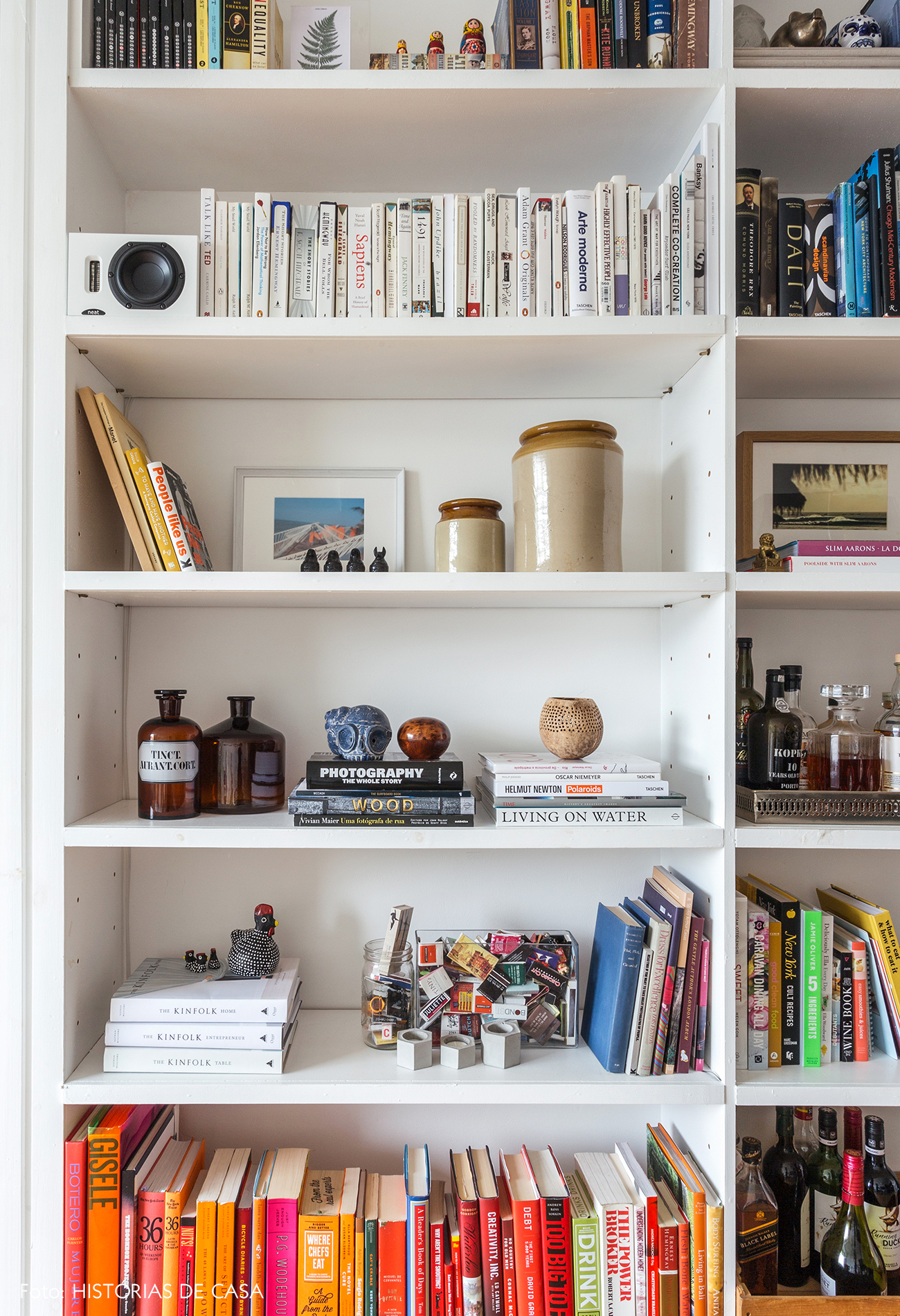 Estante branca decorada com objetos de viagem e livros coloridos