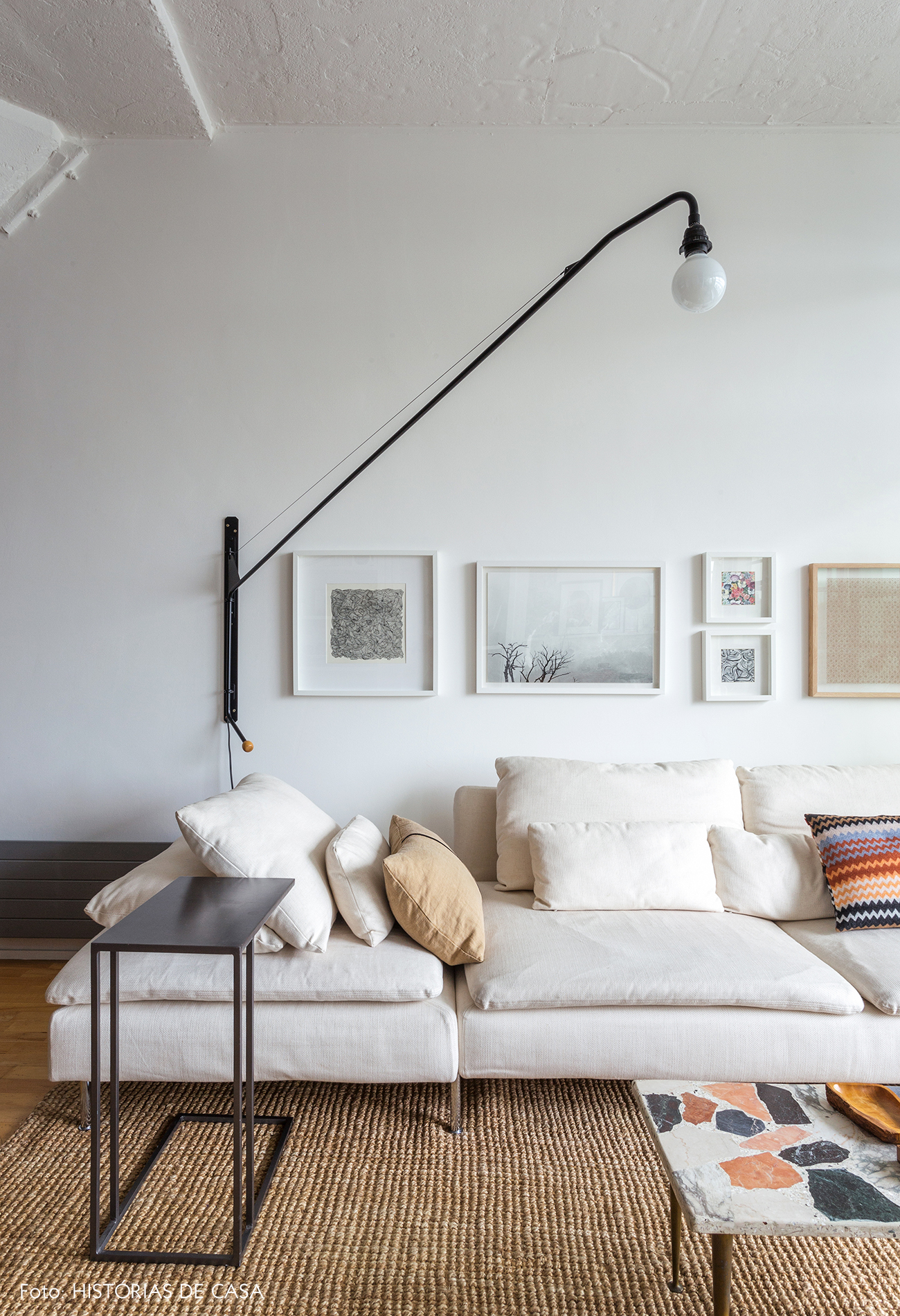 Sala com tons neutros, sofá bege e quadros