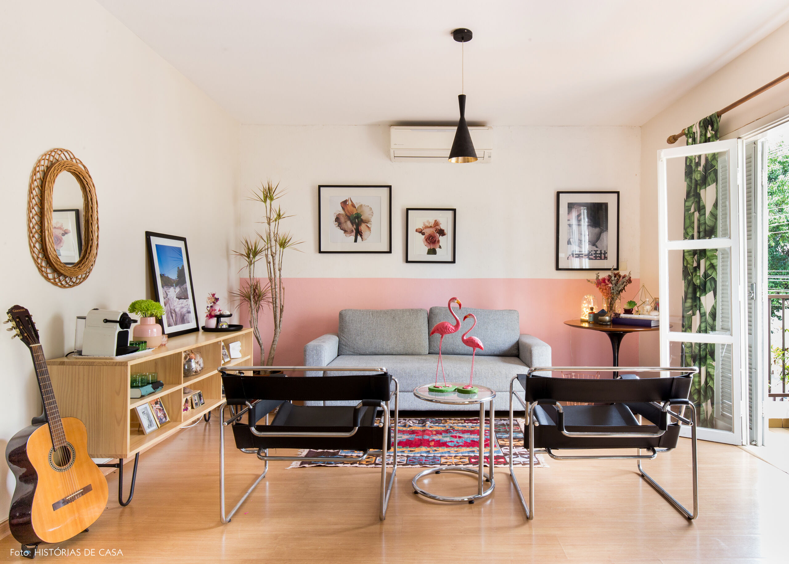 Sala com meia parede pintada de rosa e sofá cinza
