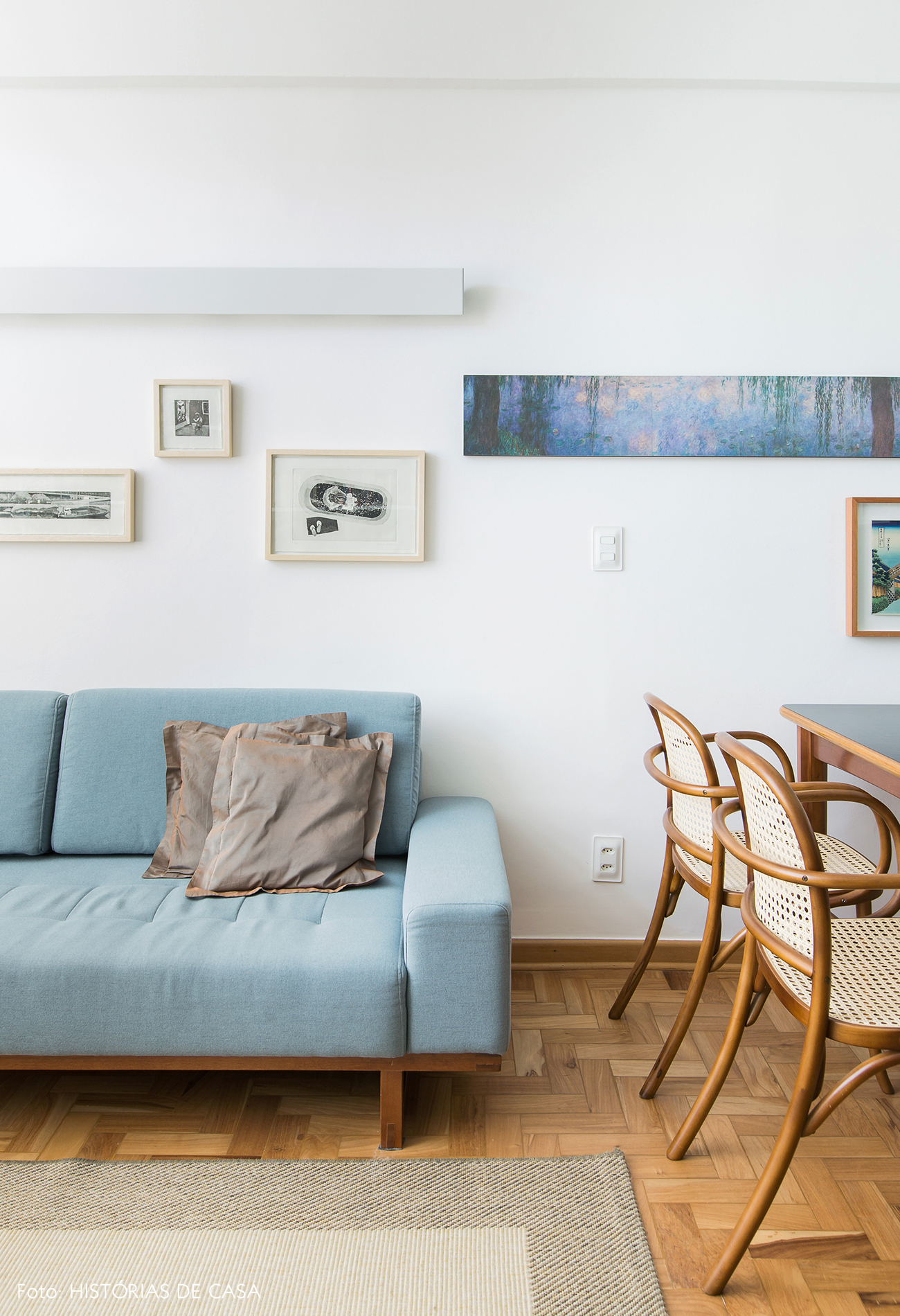 Sala pequena com sofá colorido, azul e parede de quadros