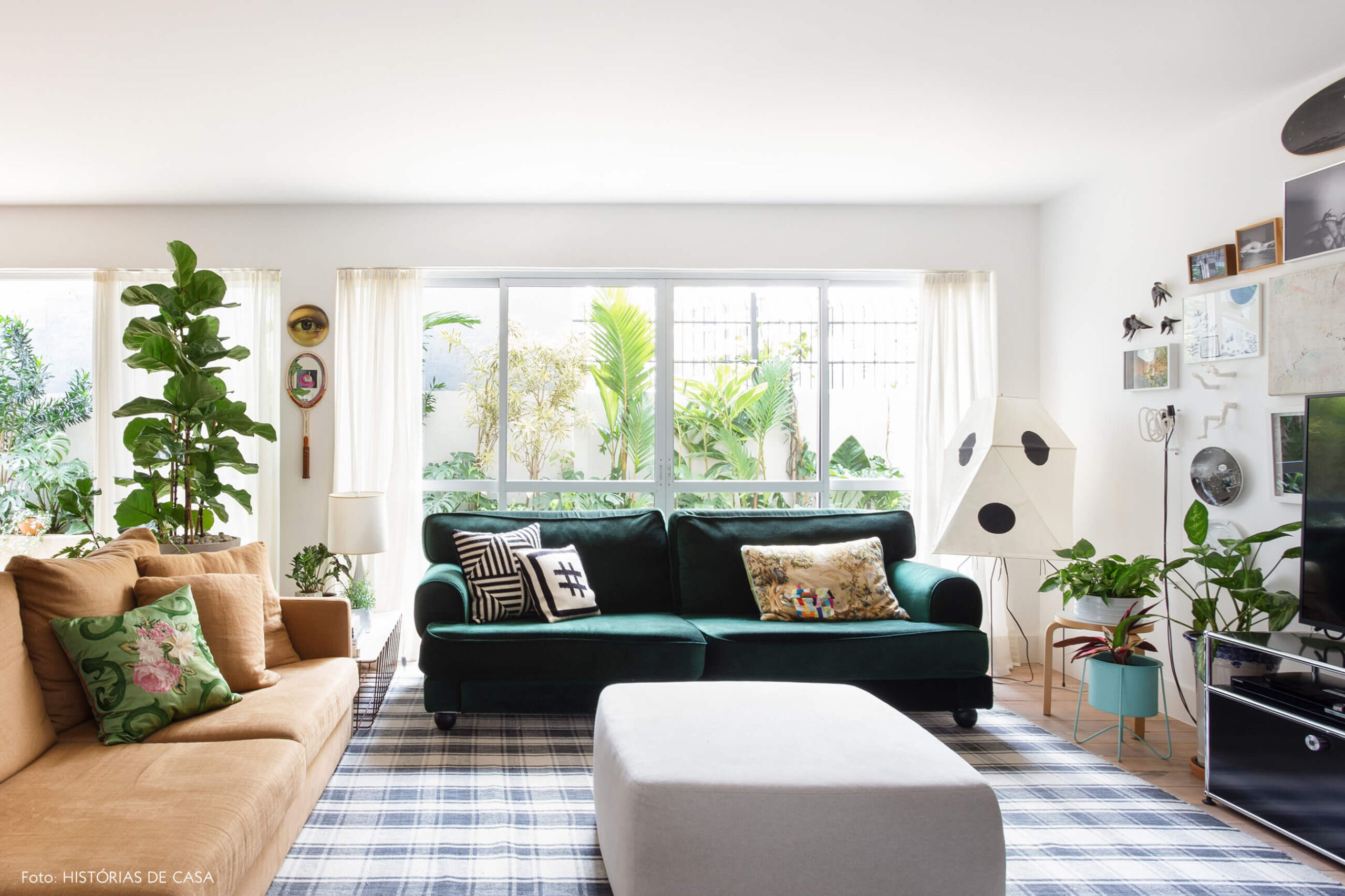 Sala com sofá de veludo verde e pufe cinza