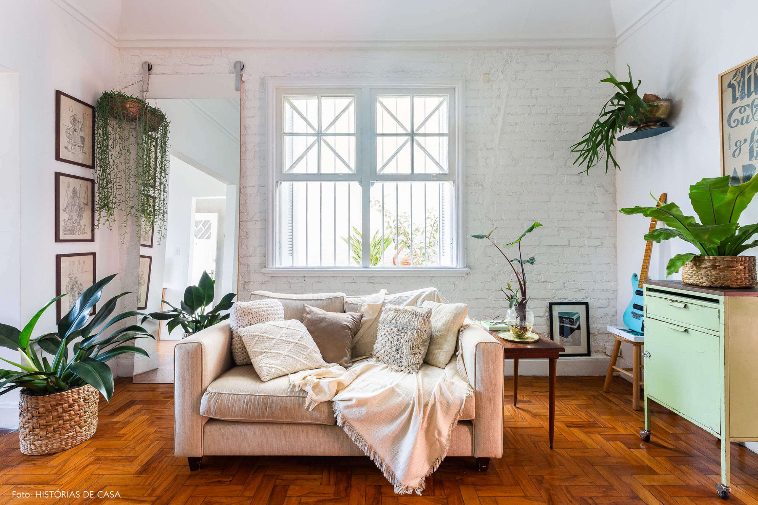Casa de vila com salas integradas, sofá bege e muitas plantas
