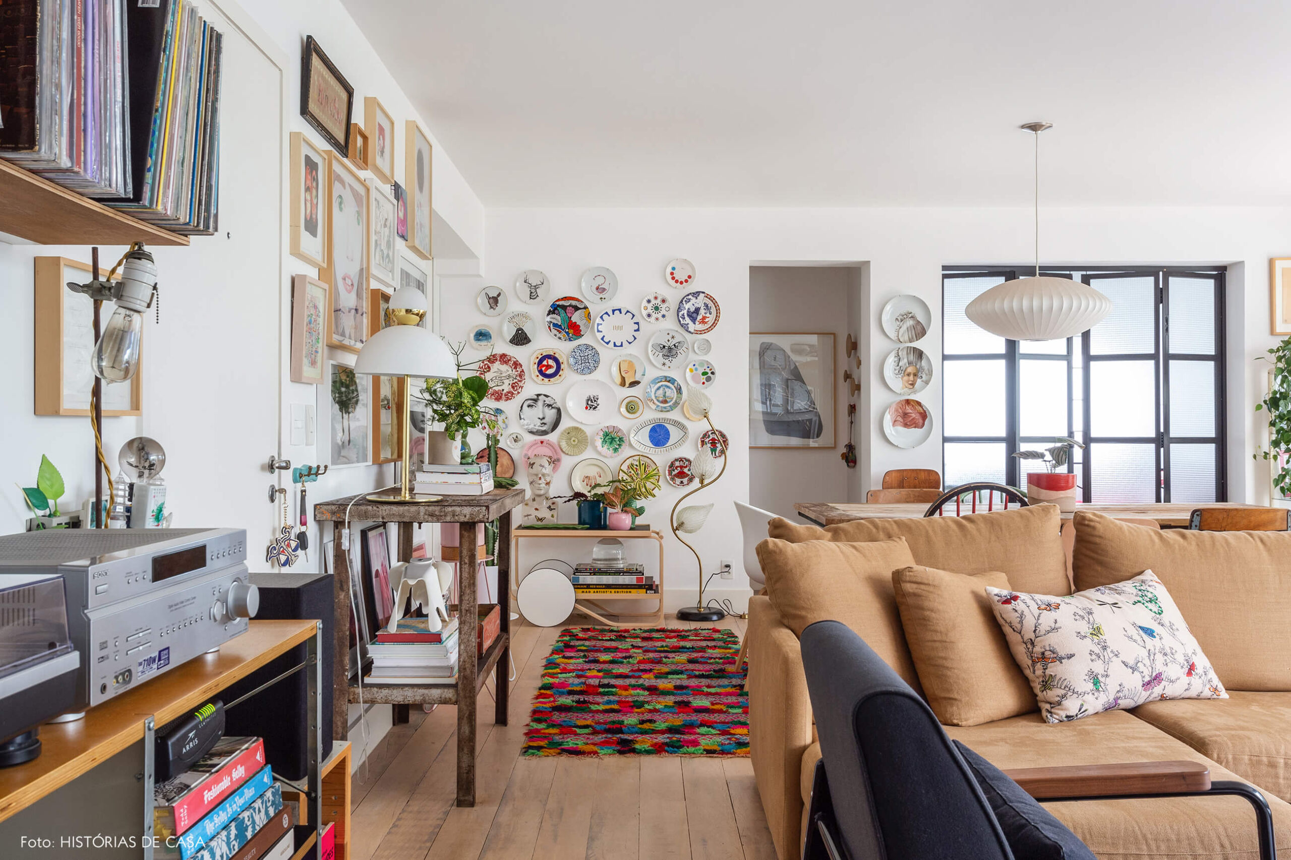 Sala com muitos quadros e sofá em tom caramelo