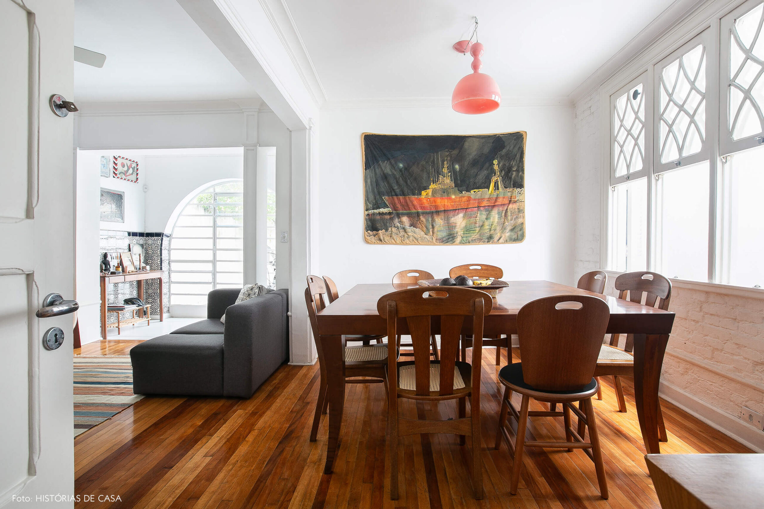 Sala de jantar com móveis de madeira e pendente rosa