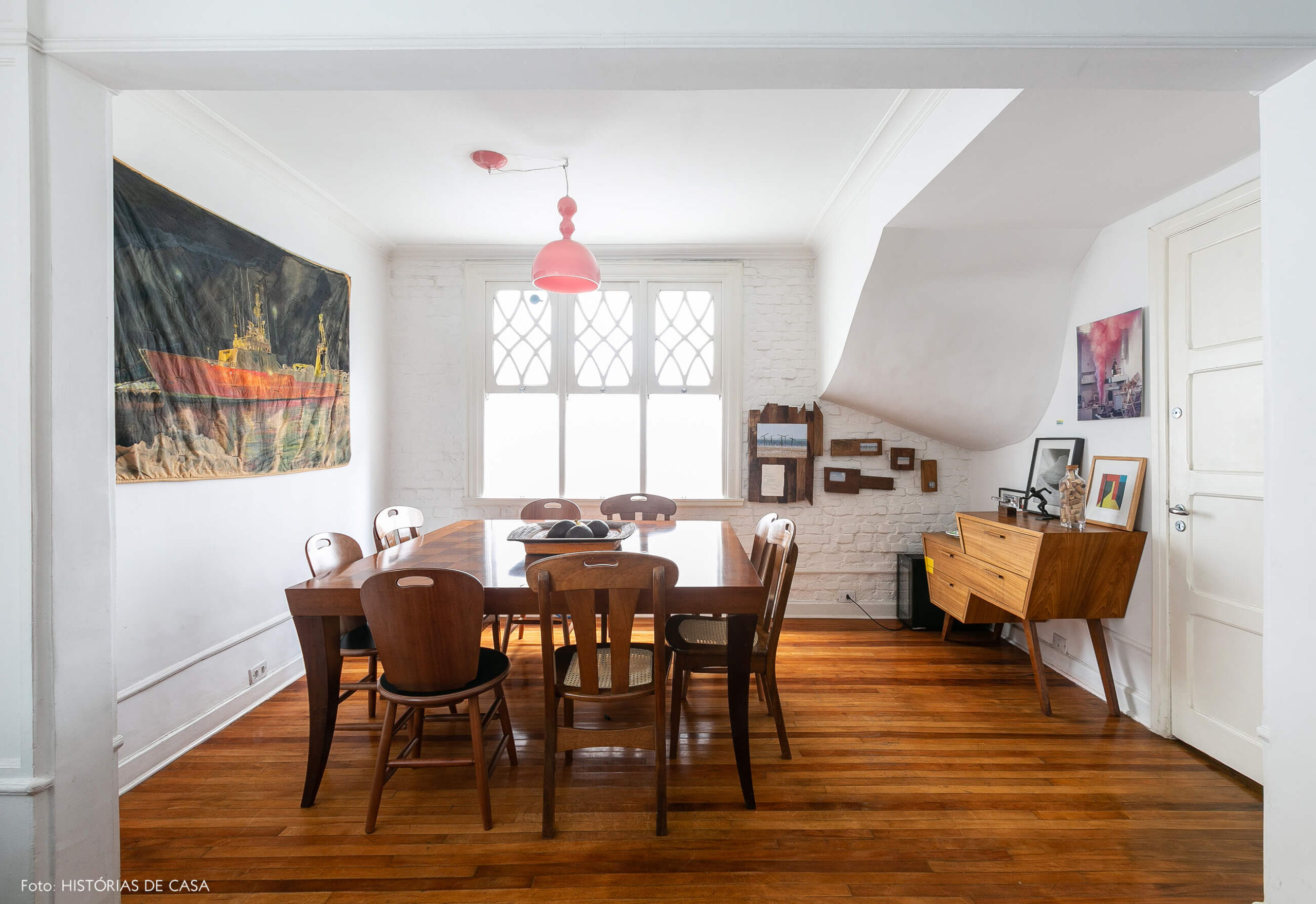Sala de jantar com móveis de madeira e pendente rosa