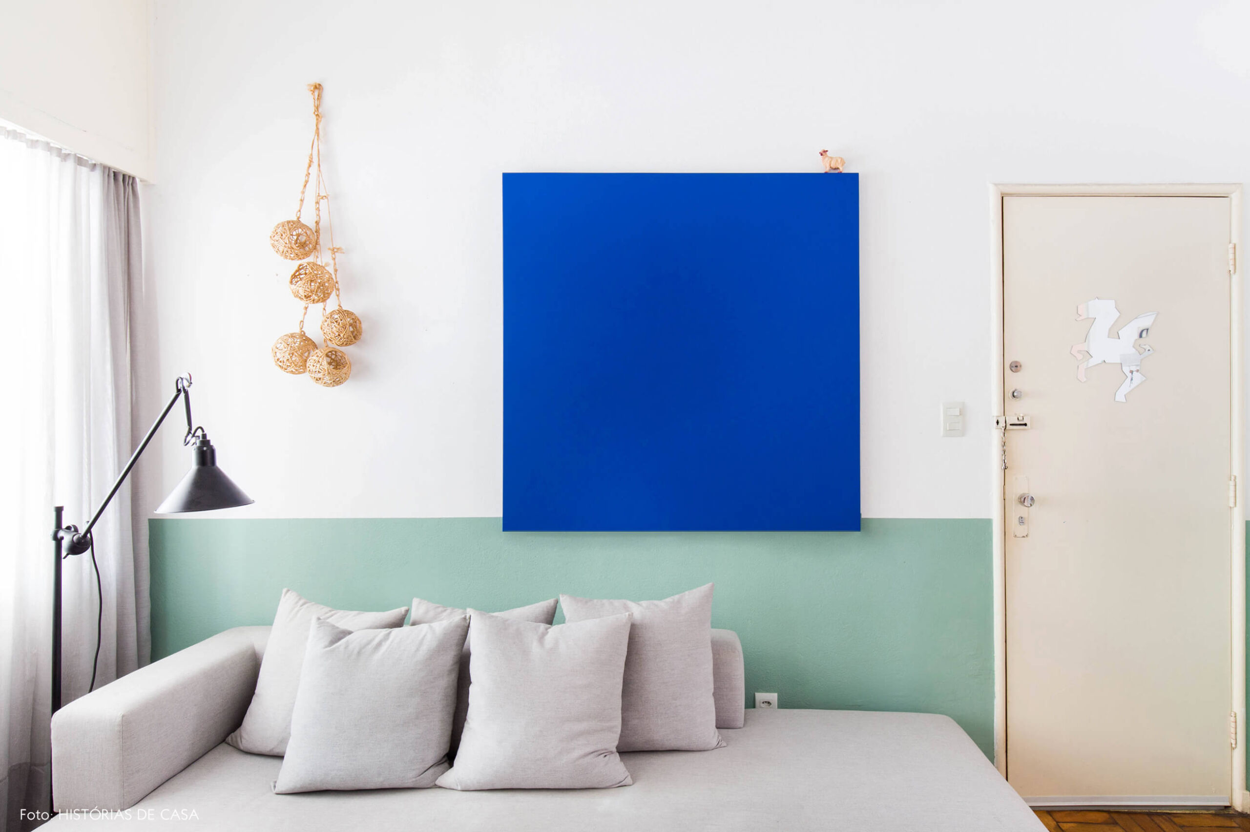 Sala com sofá cinza e meia parede verde