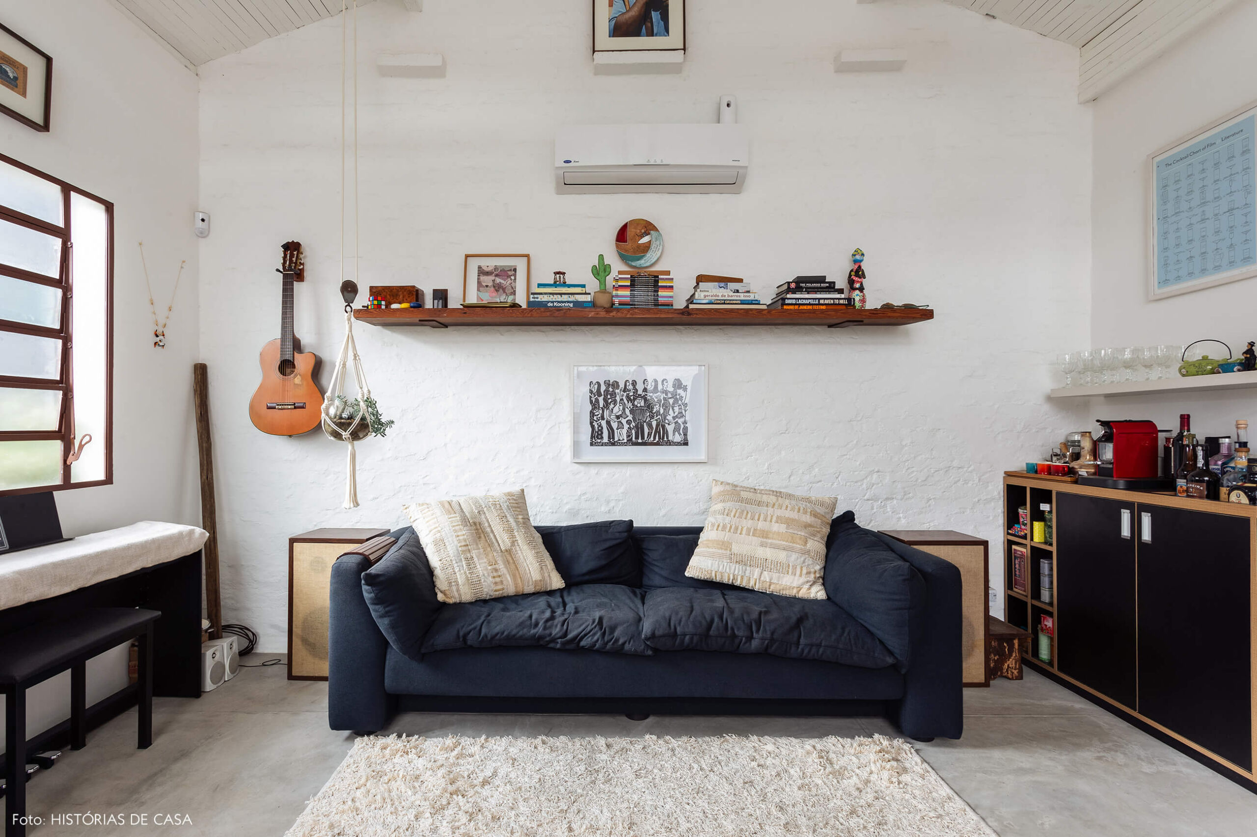 Sala com piso de cimento queimado e parede de tijolinho branco