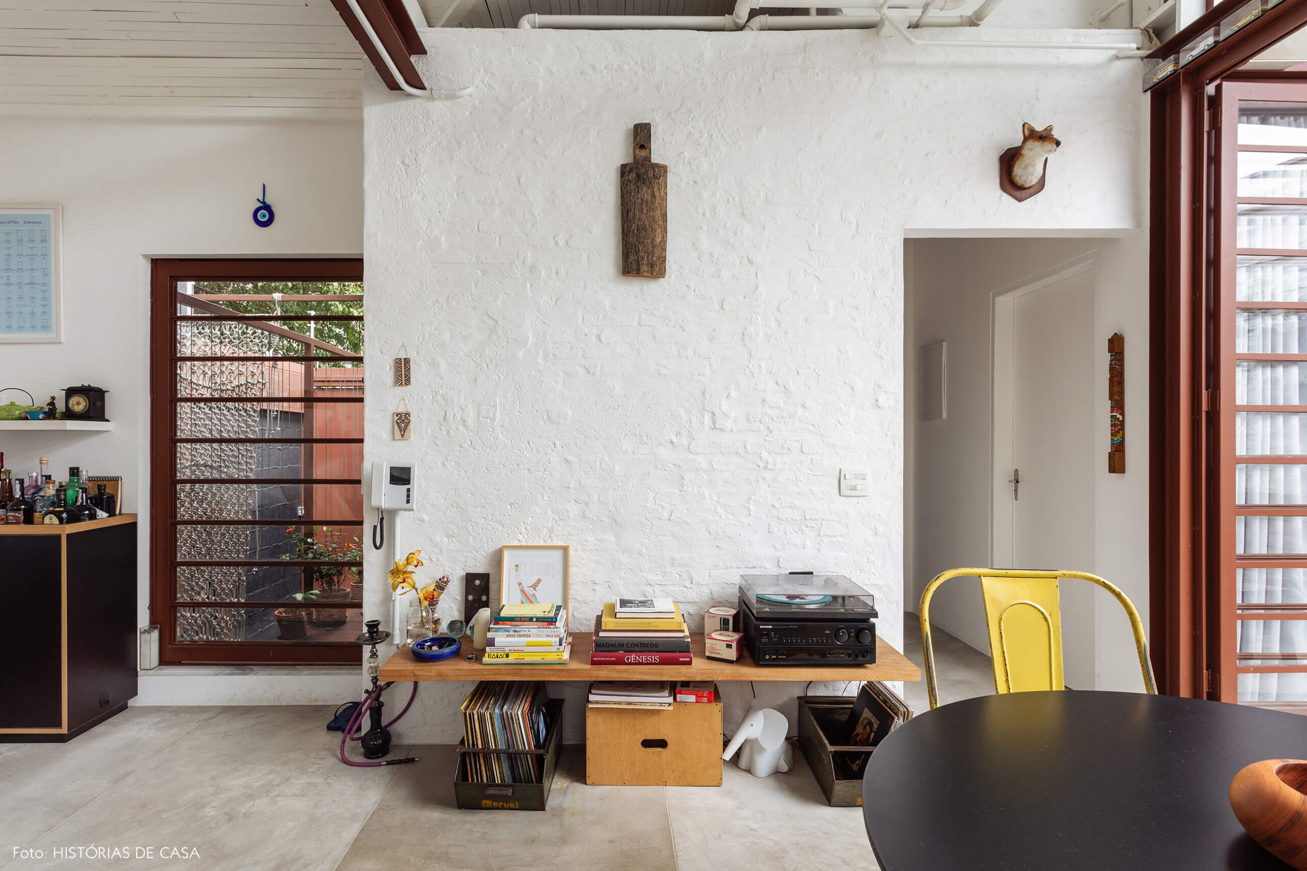 Sala com parede de tijolinho branco e prateleira baixa