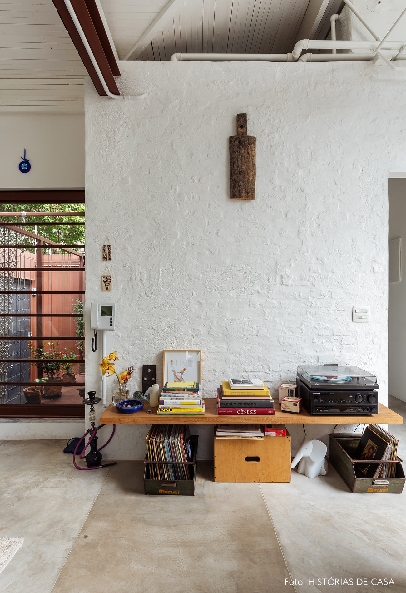 Sala com parede de tijolinho branco e prateleira baixa