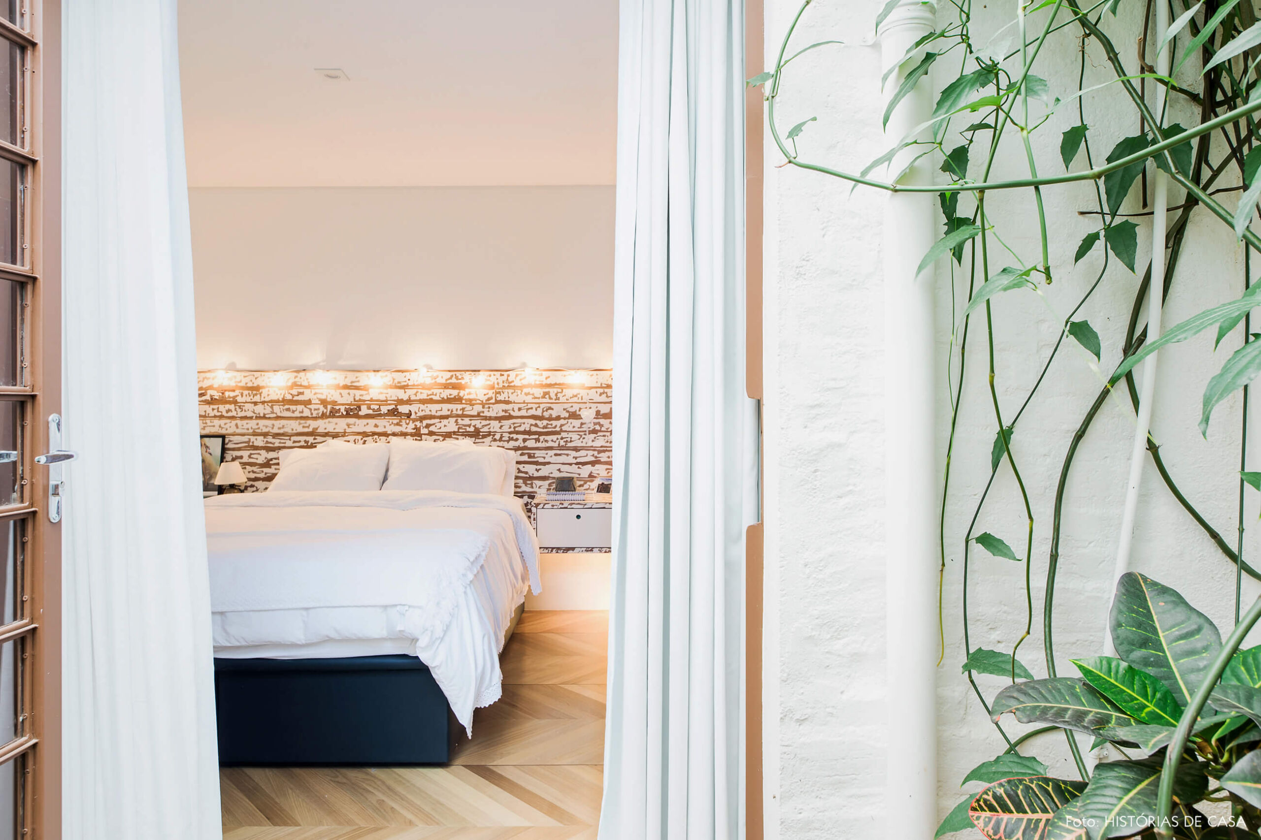 Quarto com cabeceira de madeira e fio de luzinhas