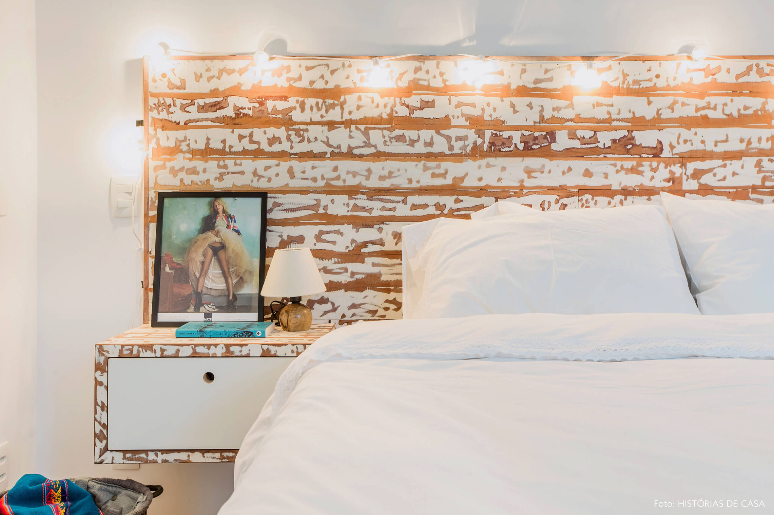 Quarto com cabeceira de madeira e fio de luzinhas