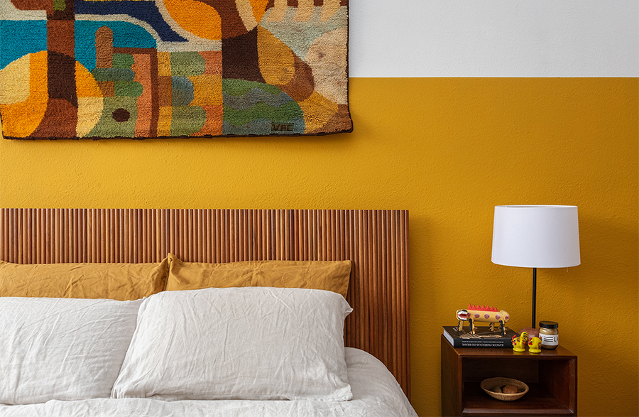 Quarto com parede mostarda e cabeceira de madeira