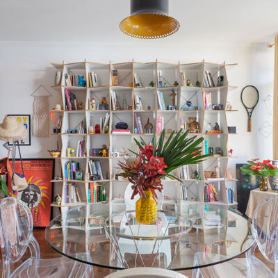 Sala com estante branca e mesa de vidro