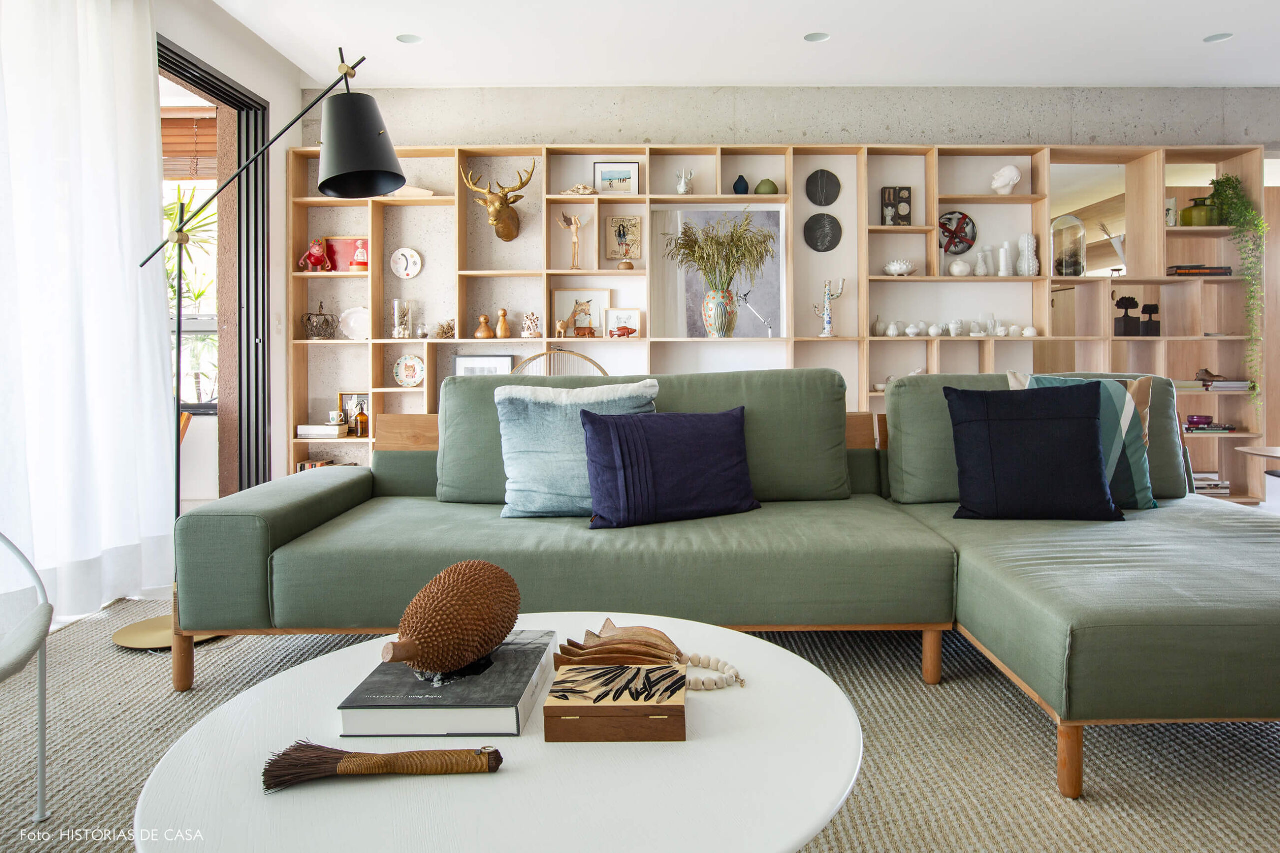 Sala com sofá verde e estante de madeira clara