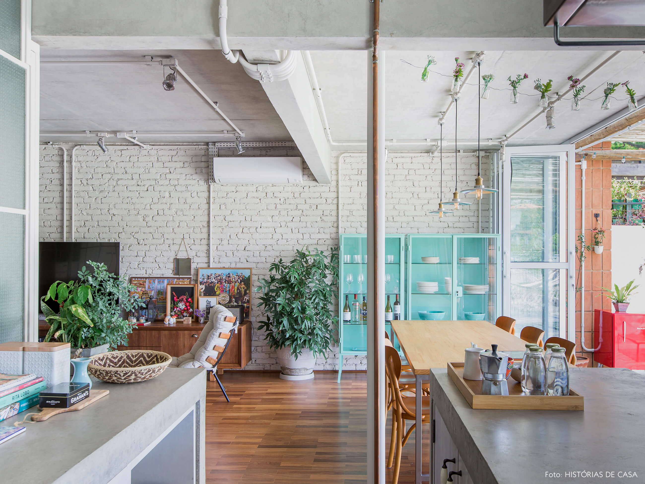Sala de jantar integrada com paredes de tijolinho e cristaleira colorida