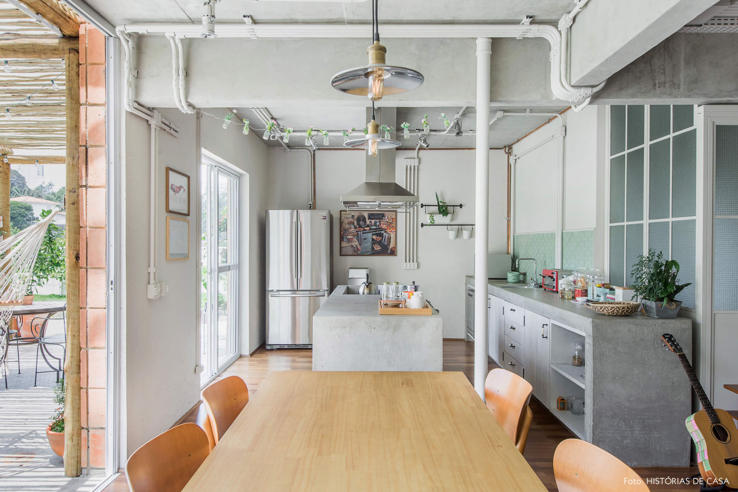 Sala de jantar integrada com a cozinha, com estruturas de concreto aparente