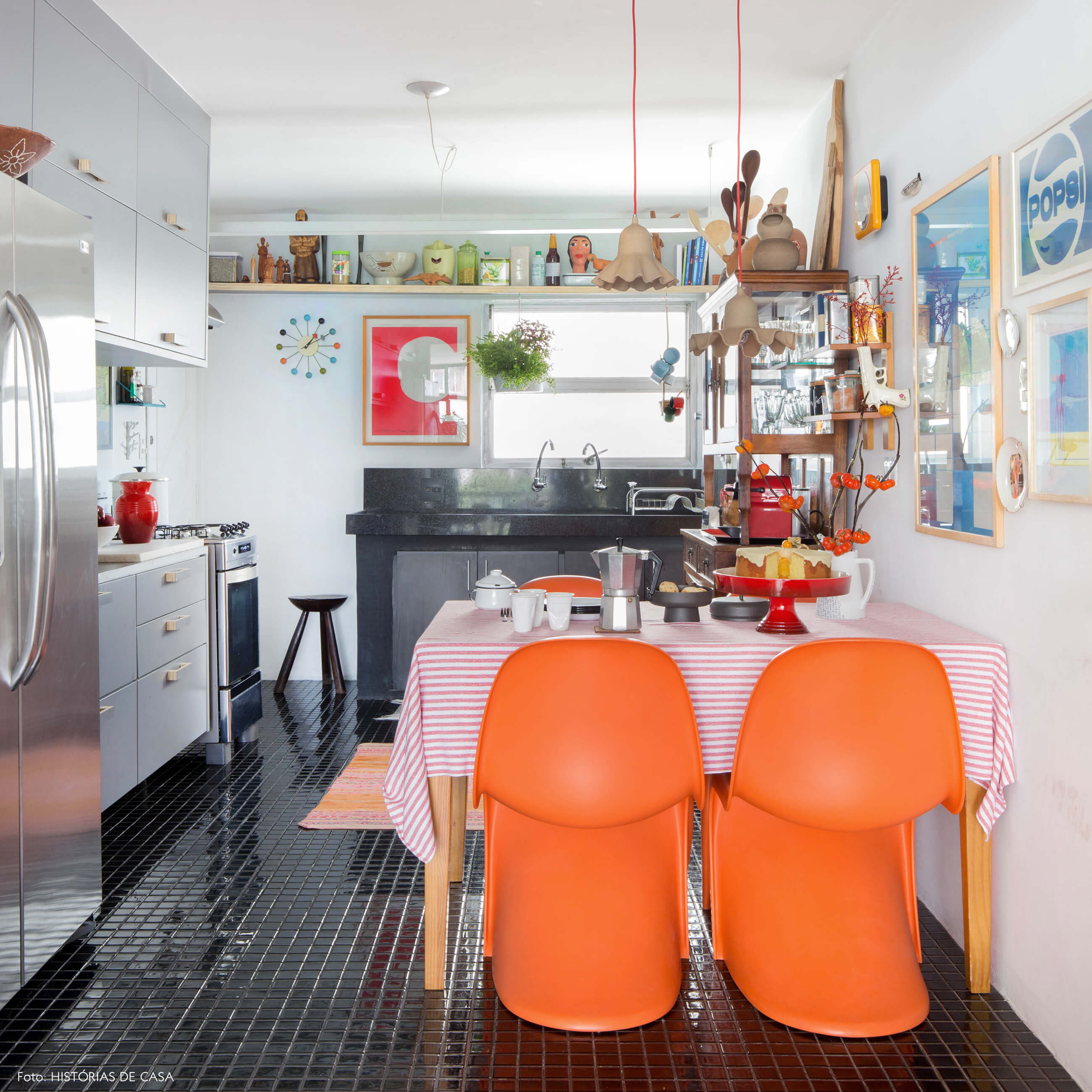 Cozinha com piso preto e cadeiras Panton laranja