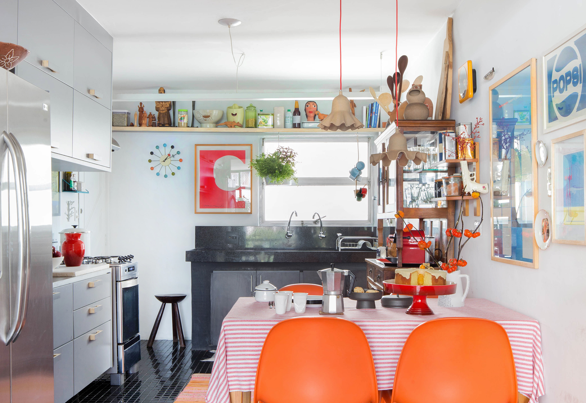 Cozinha com cadeiras laranja e acabamentos pretos