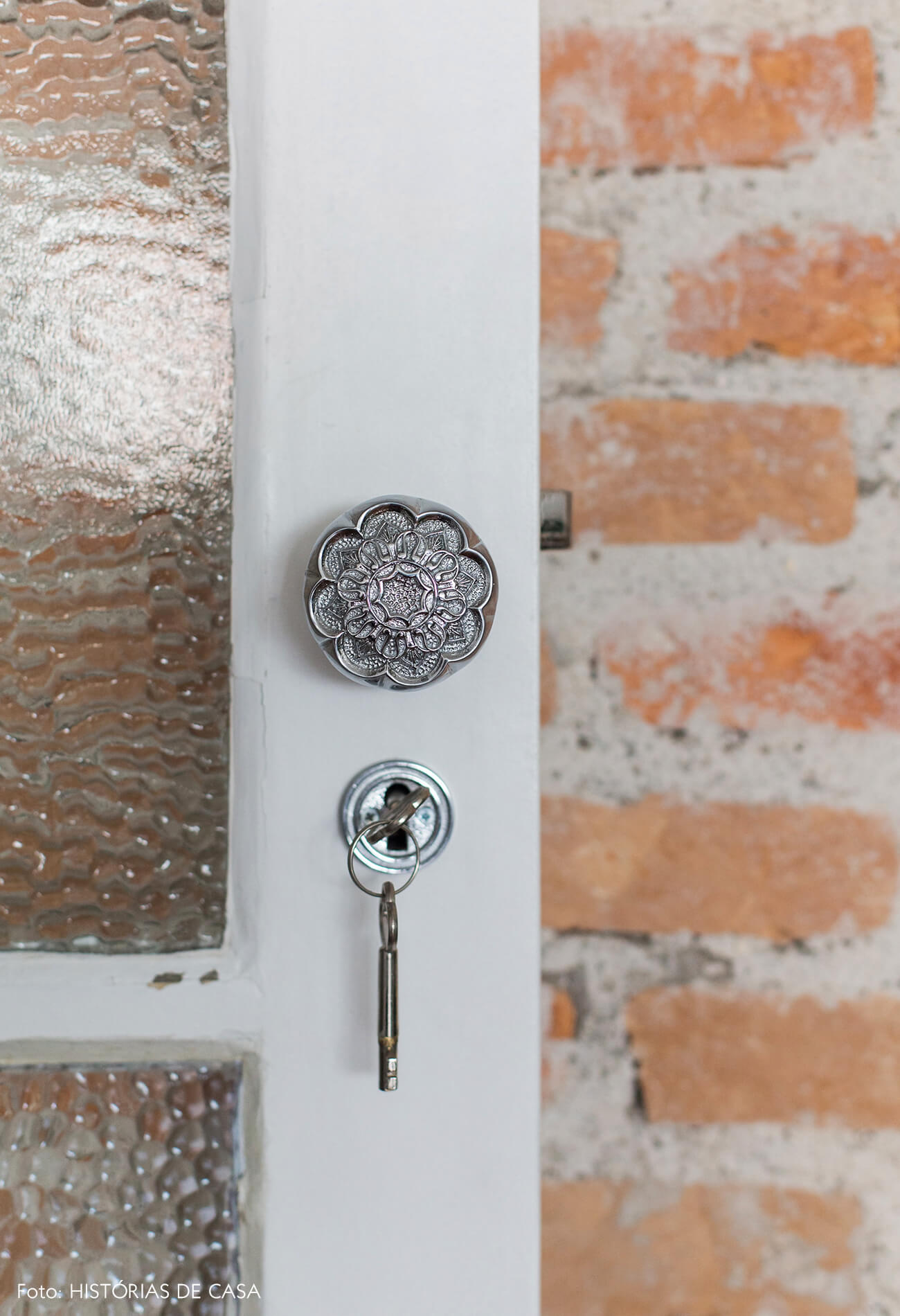 Sala integrada com parede de tijolinho aparente e maçanetas antigas