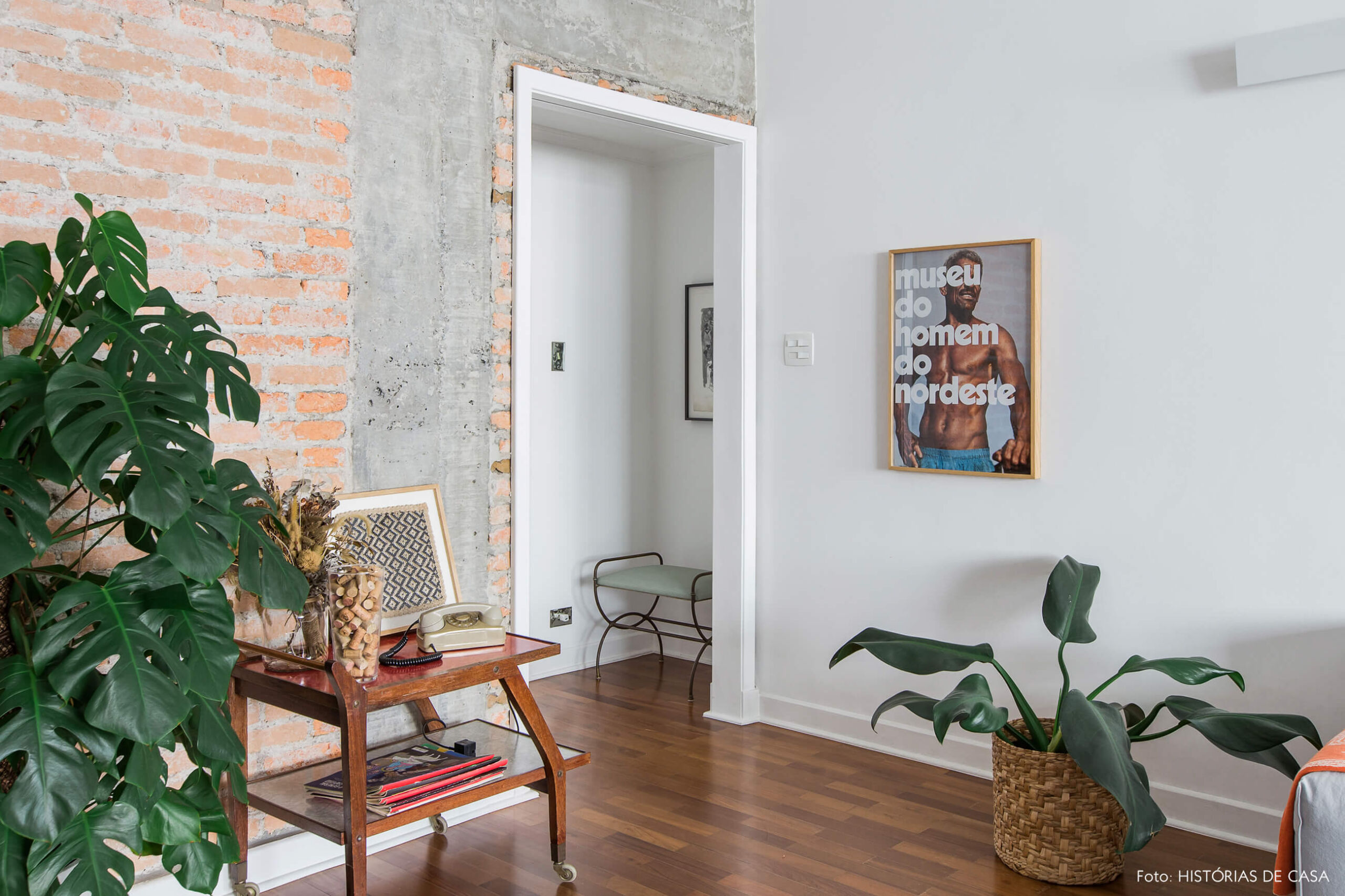 Sala integrada com piso de madeira e parede de tijolinho