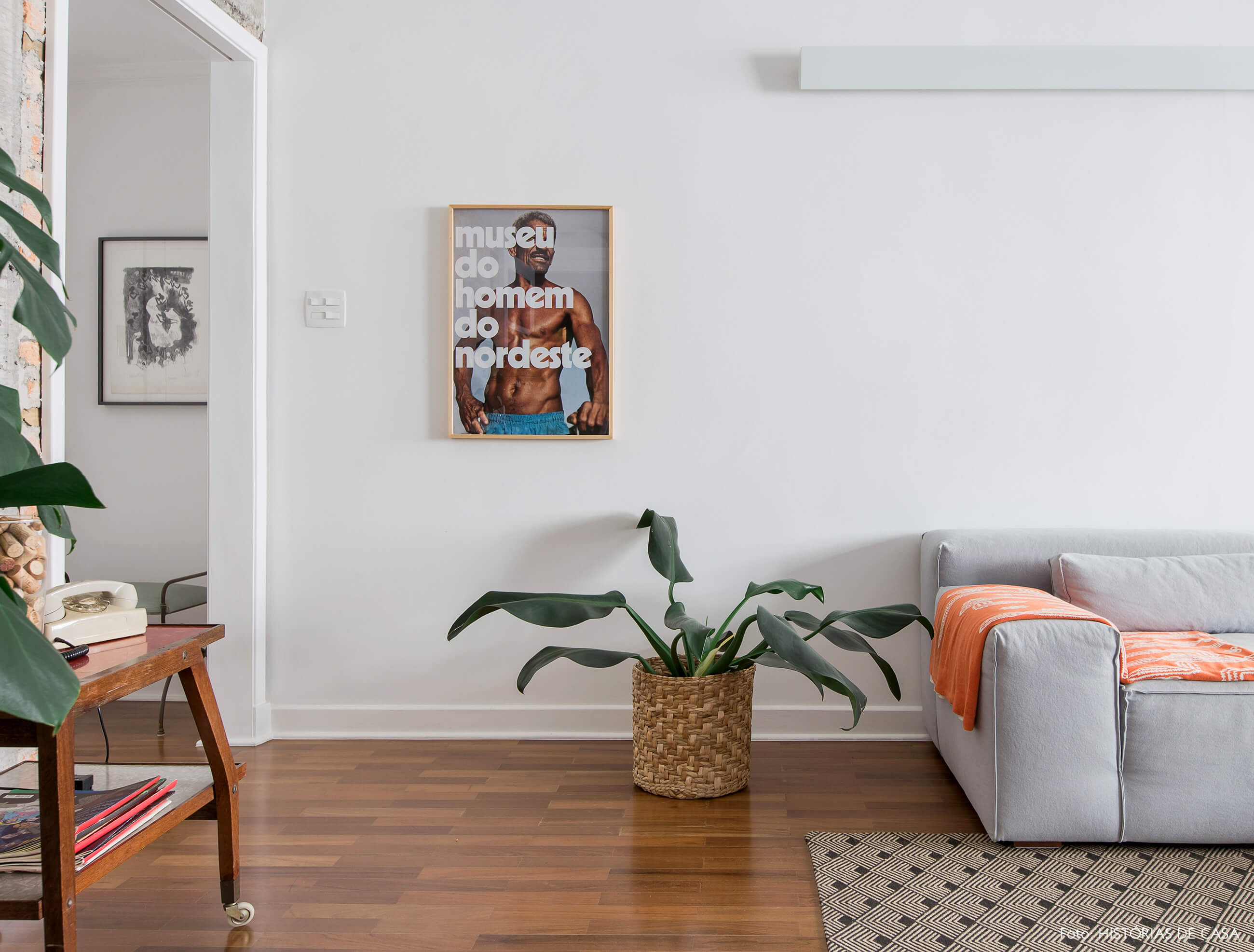 Sala integrada com piso de madeira e sofá cinza