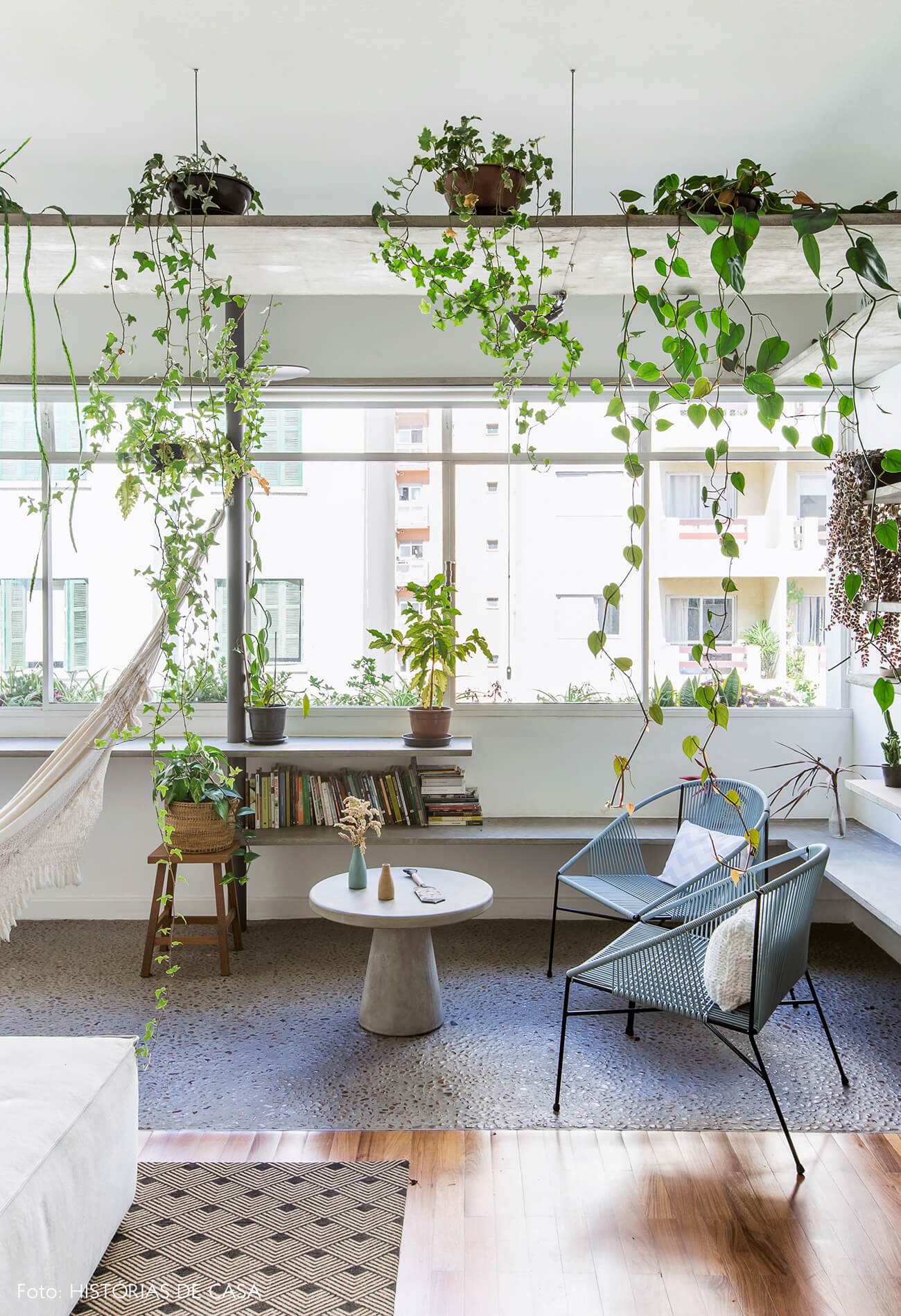 Sala com varanda integrada, piso de seixos e prateleiras de concreto com plantas