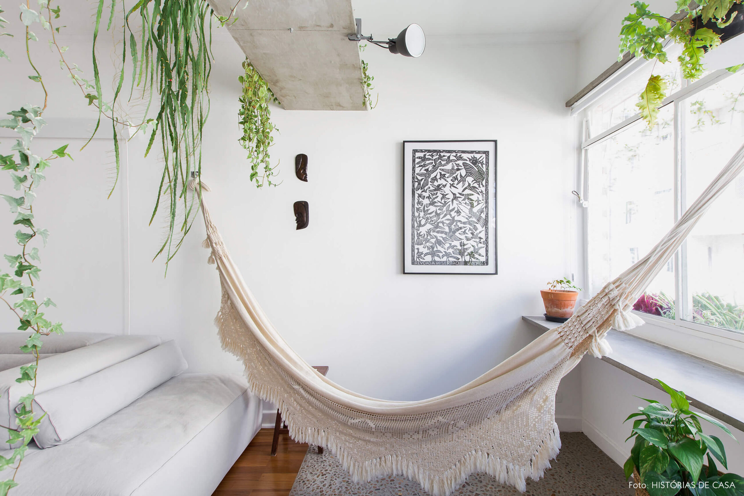 Sala com varanda integrada, prateleiras de concreto com plantas e rede de balanço