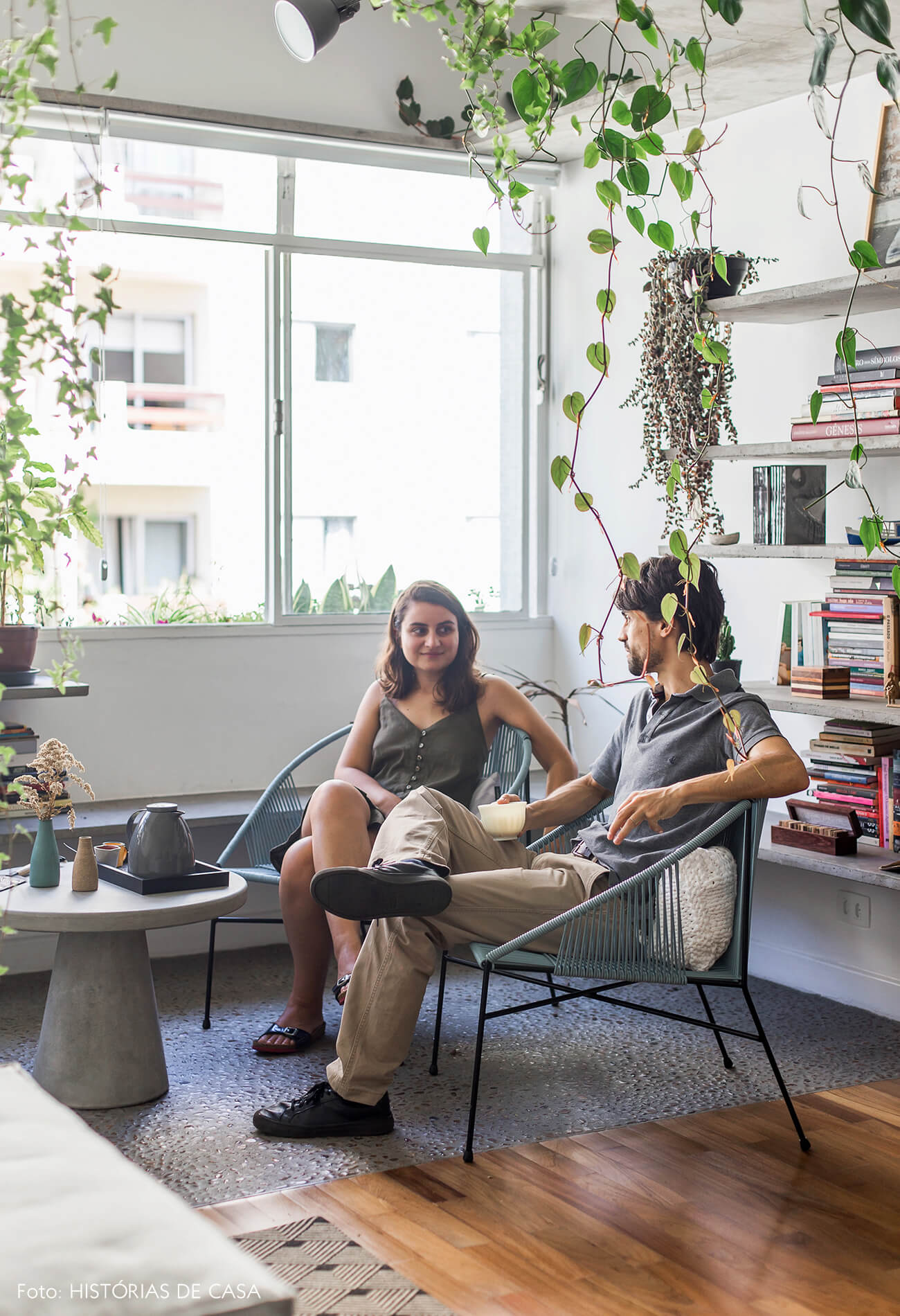 Sala com varanda integrada, piso de seixos e prateleiras de concreto com plantas