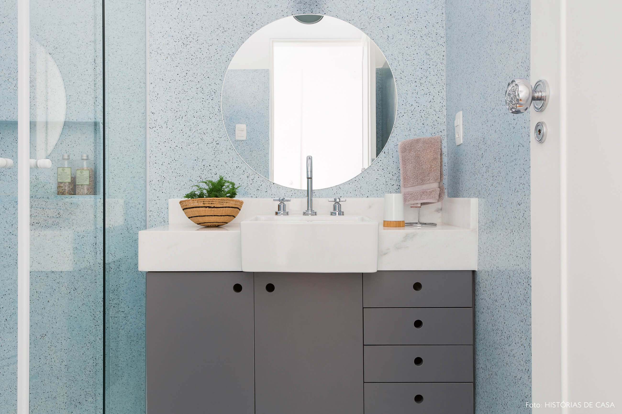 Banheiro de granilite azul no piso e na parede, espelho redondo