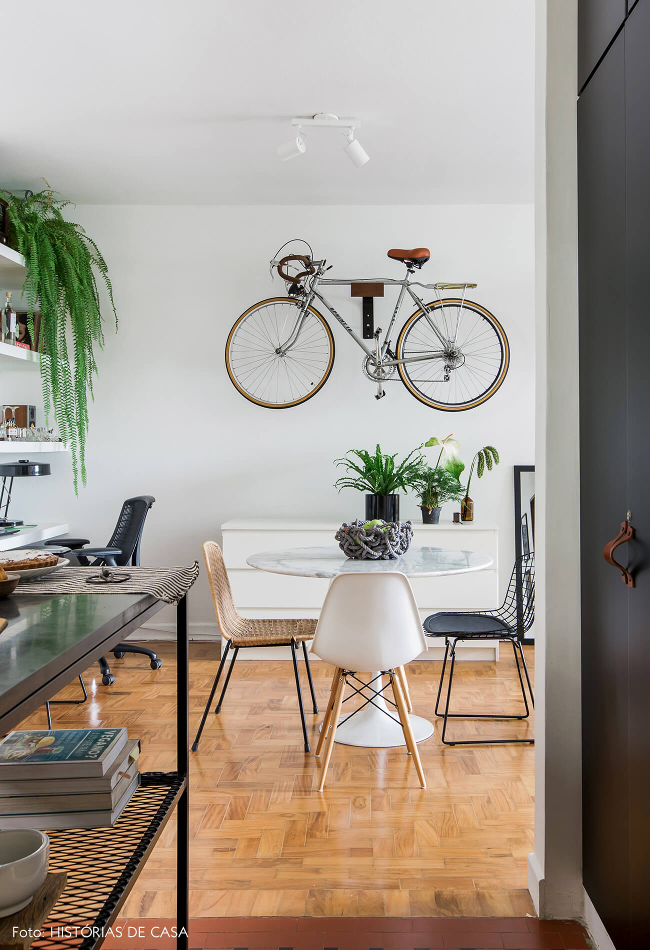 Sala de jantar com mesa tulipa redonda e suporte de bicicleta na parede