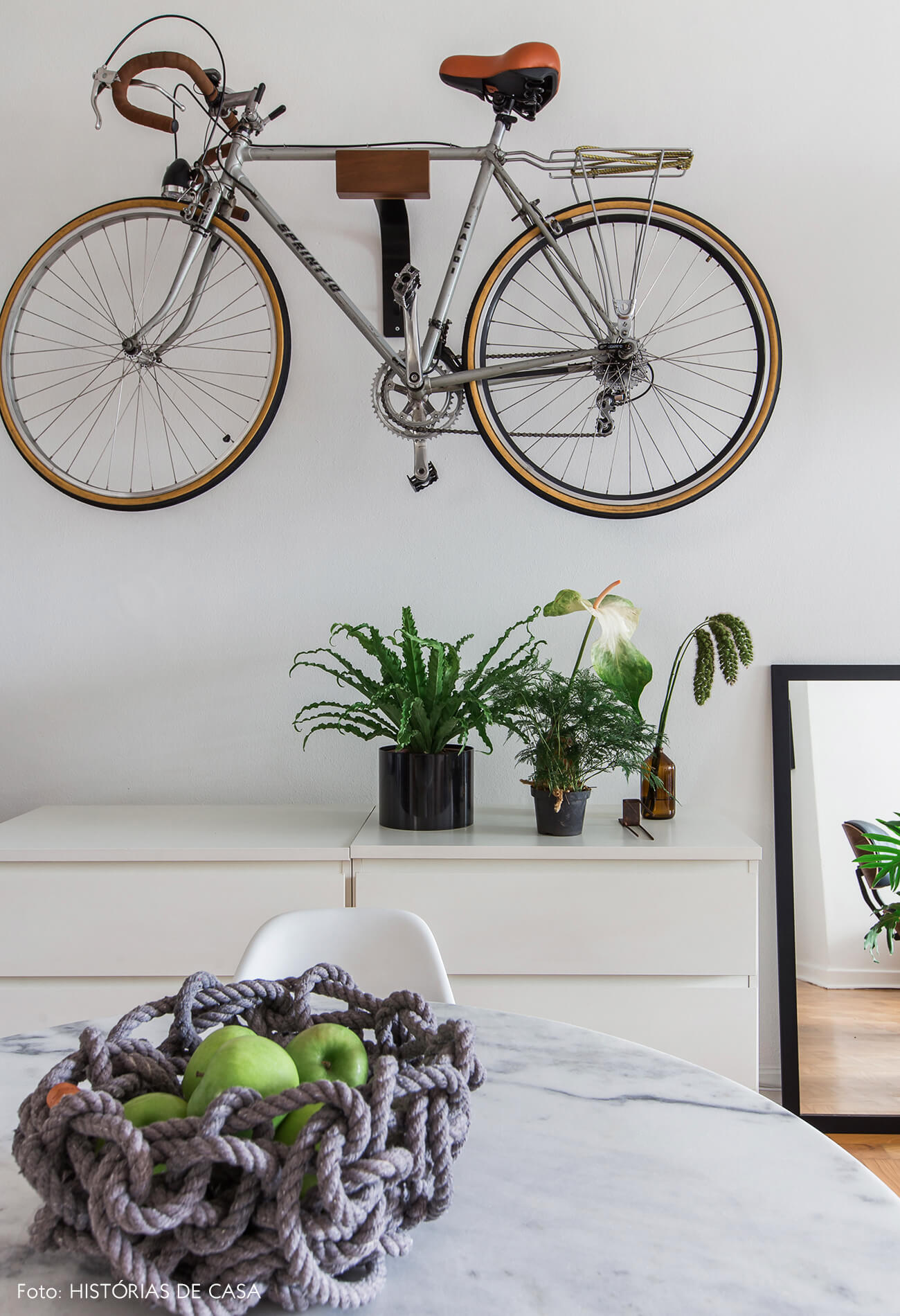 Sala de jantar com mesa tulipa redonda e suporte de bicicleta na parede
