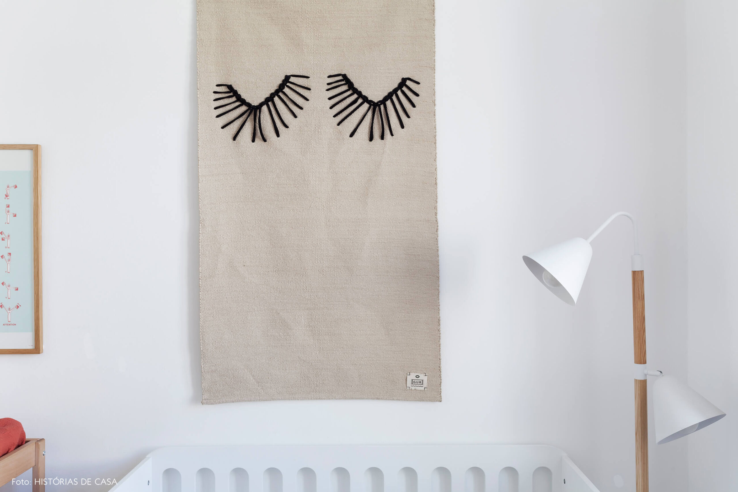 Quarto de bebê com berço branco e tapeçaria