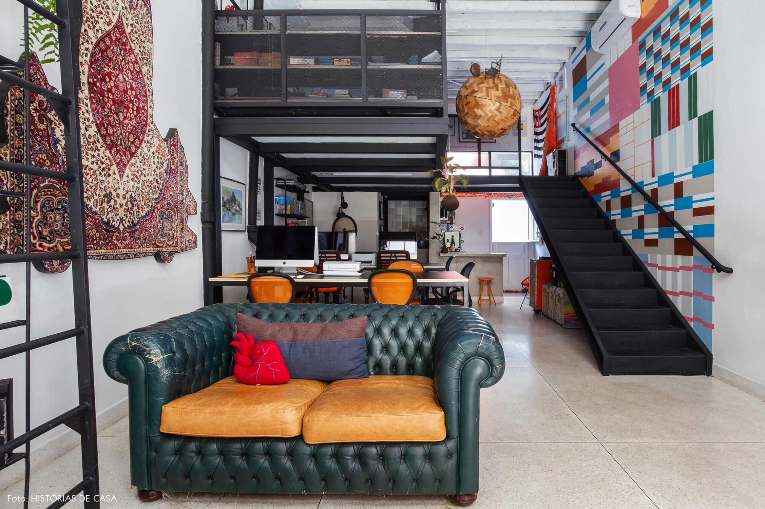 Novo escritório da imobiliária Refúgios Urbanos, sofá vintage de couro e espaço com mezanino