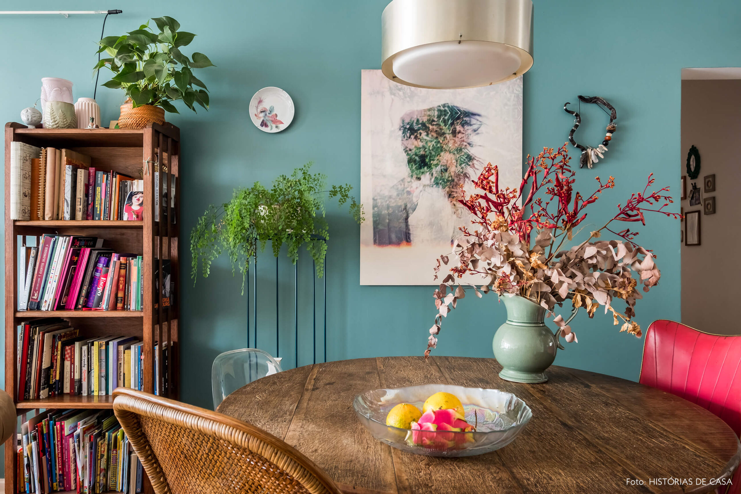 Sala de jantar com mesa redonda e parede pintada de azul, móveis rústicos de madeira