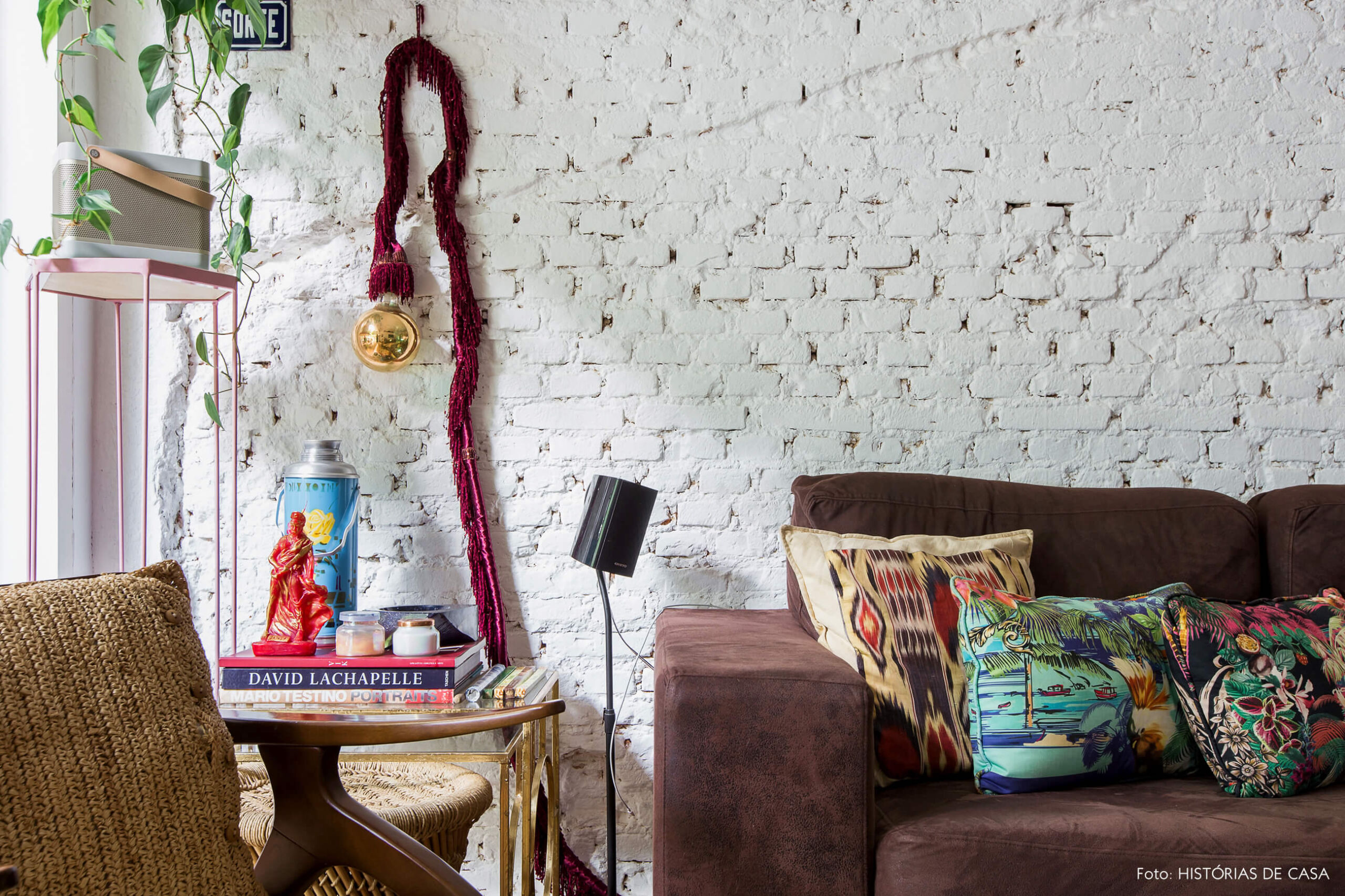 Casa com decoração eclética, parede de tijolinhos brancos e sofá escuro