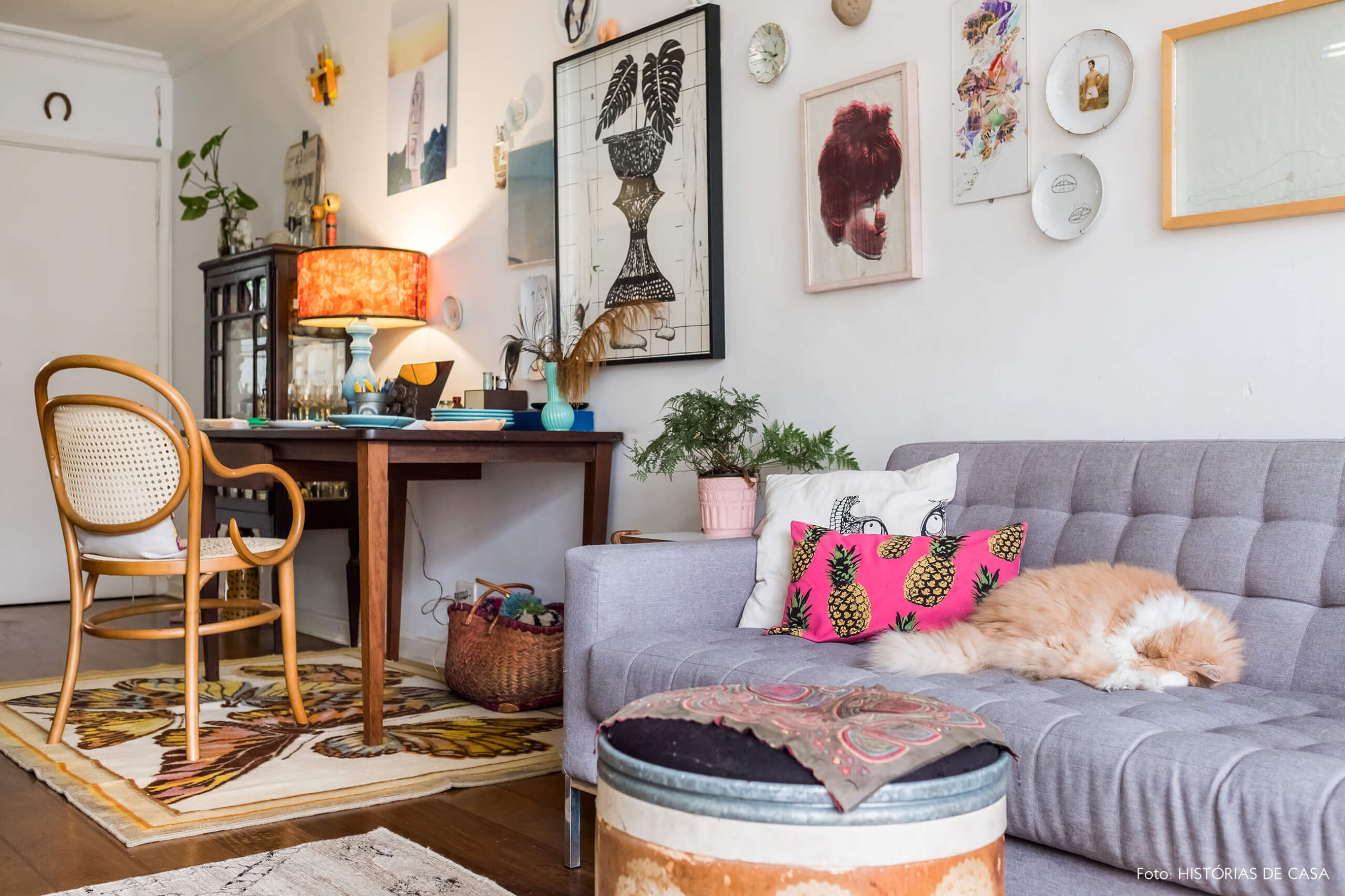 Sala com sofá cinza, quadrinhos e home office