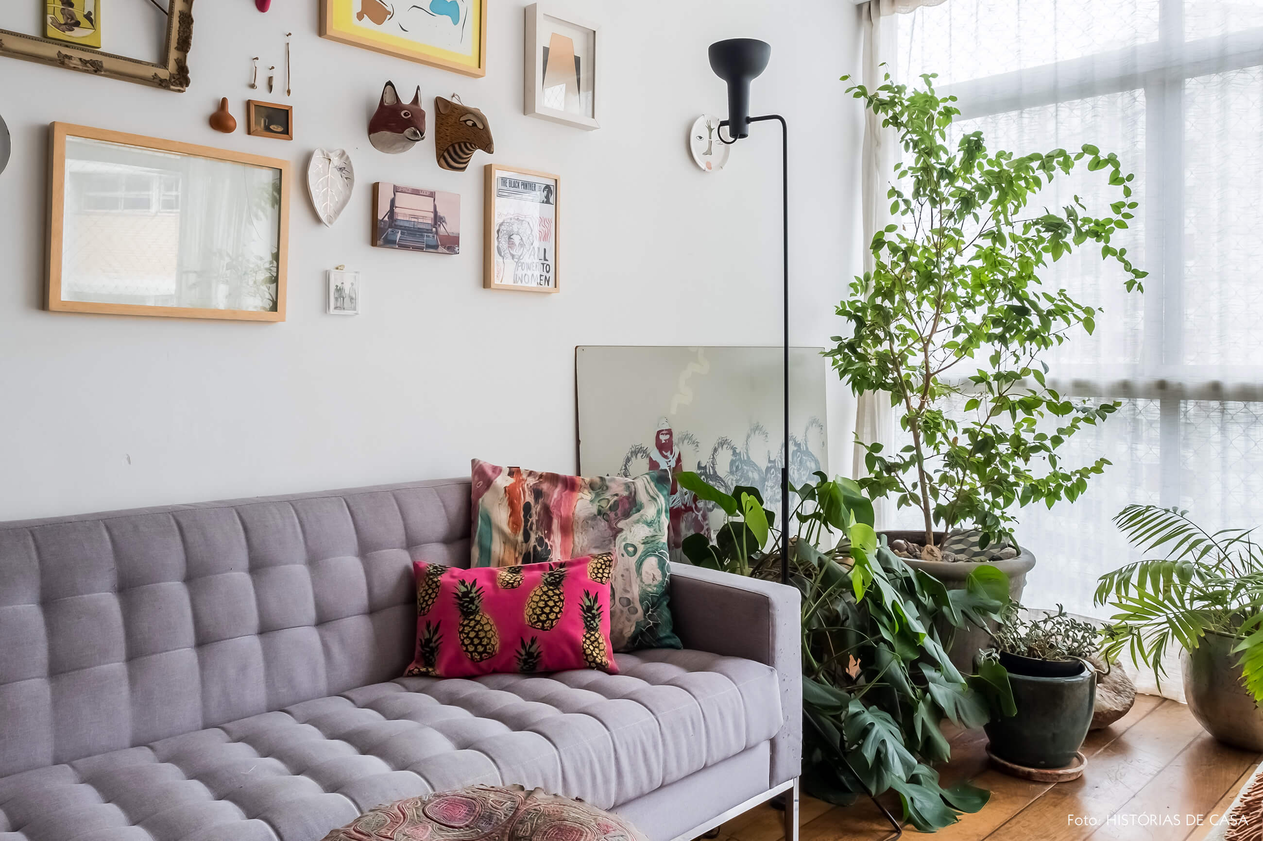 Sala com sofá cinza e muitas plantas