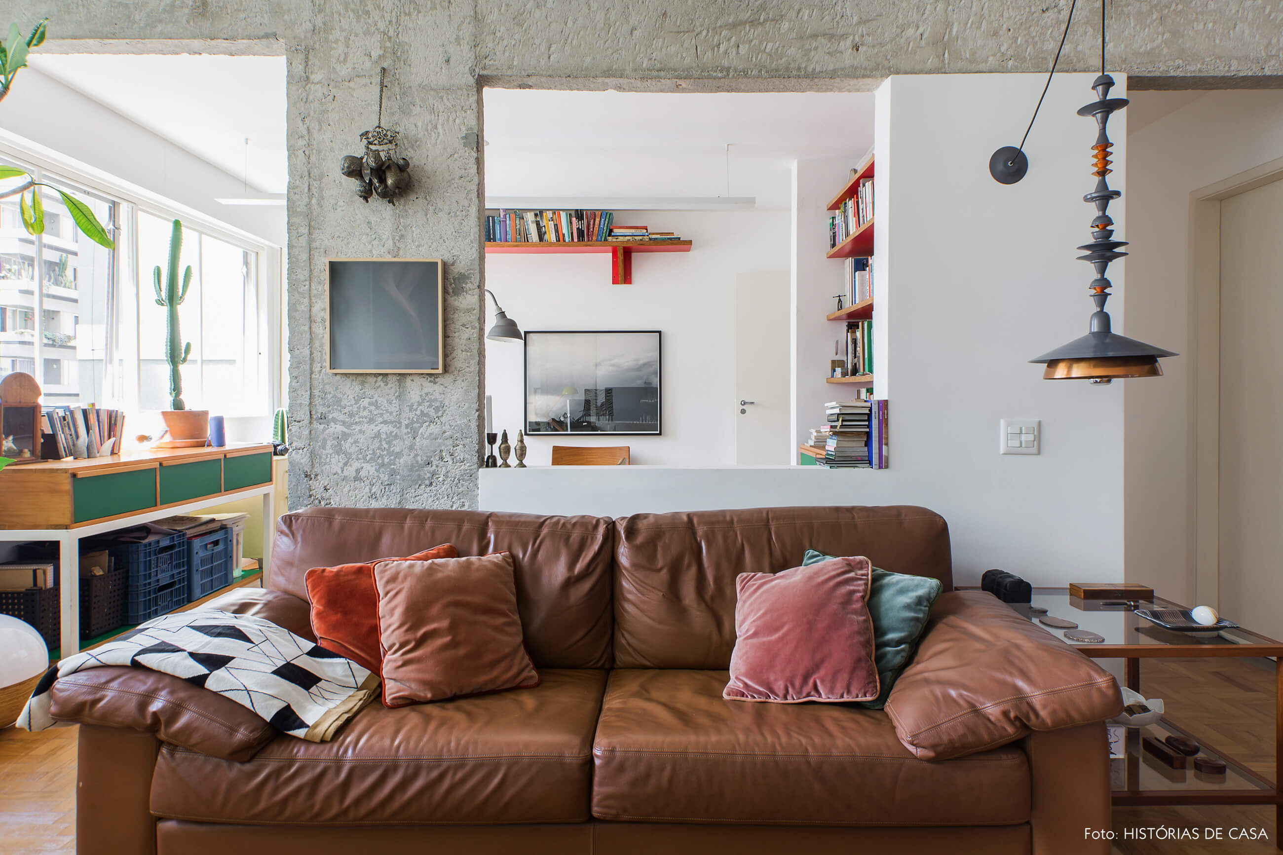 Sala com sofá de couro marrom e janela integrada para home office