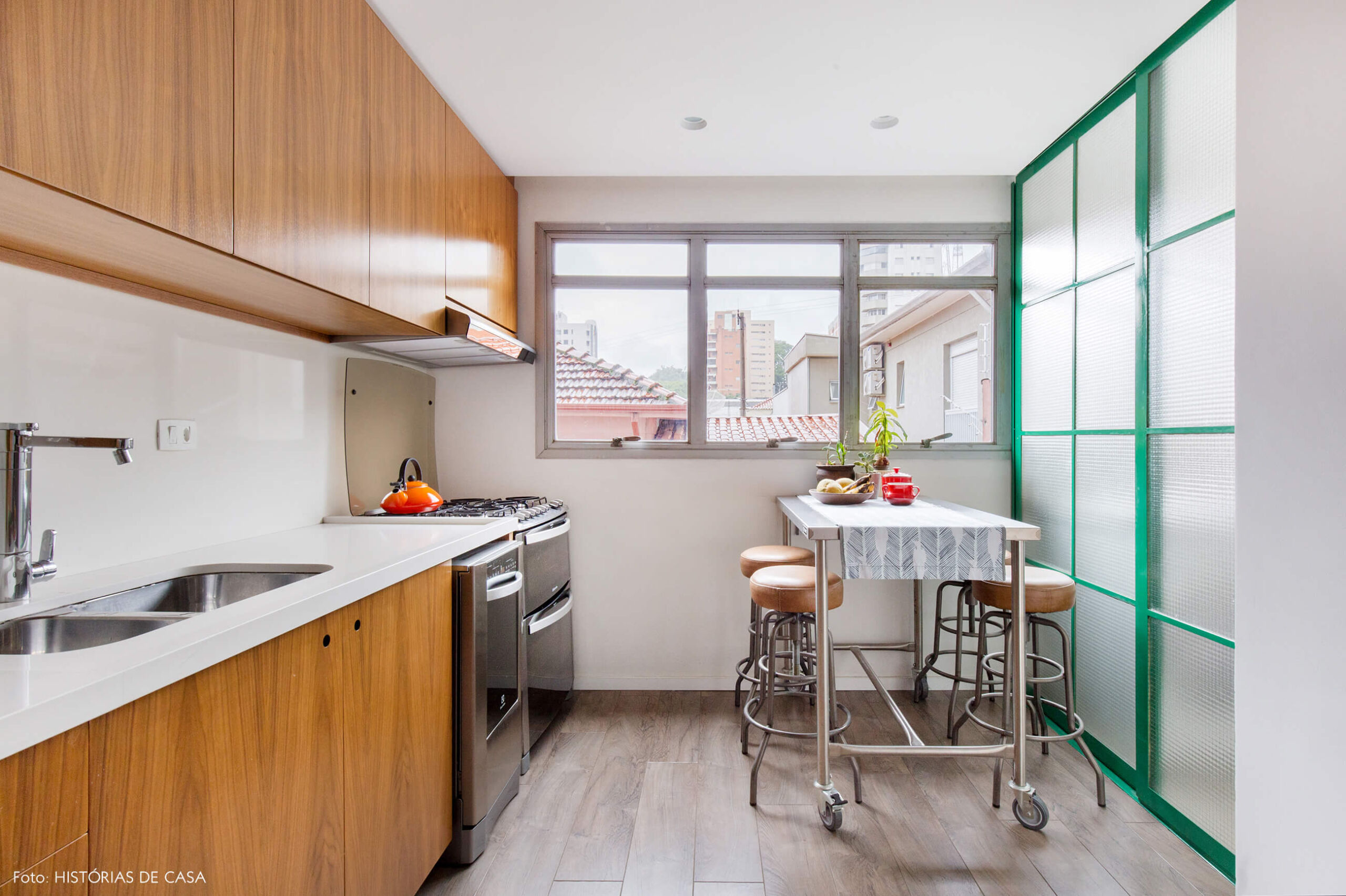 Cozinha reformada com bancada industrial com rodinhas e porta de serralheria verde