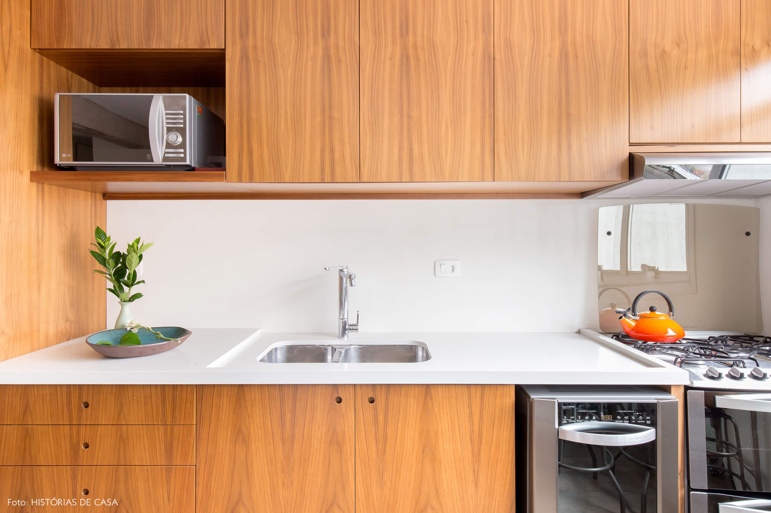 Cozinha reformada com bancada branca e armários de madeira