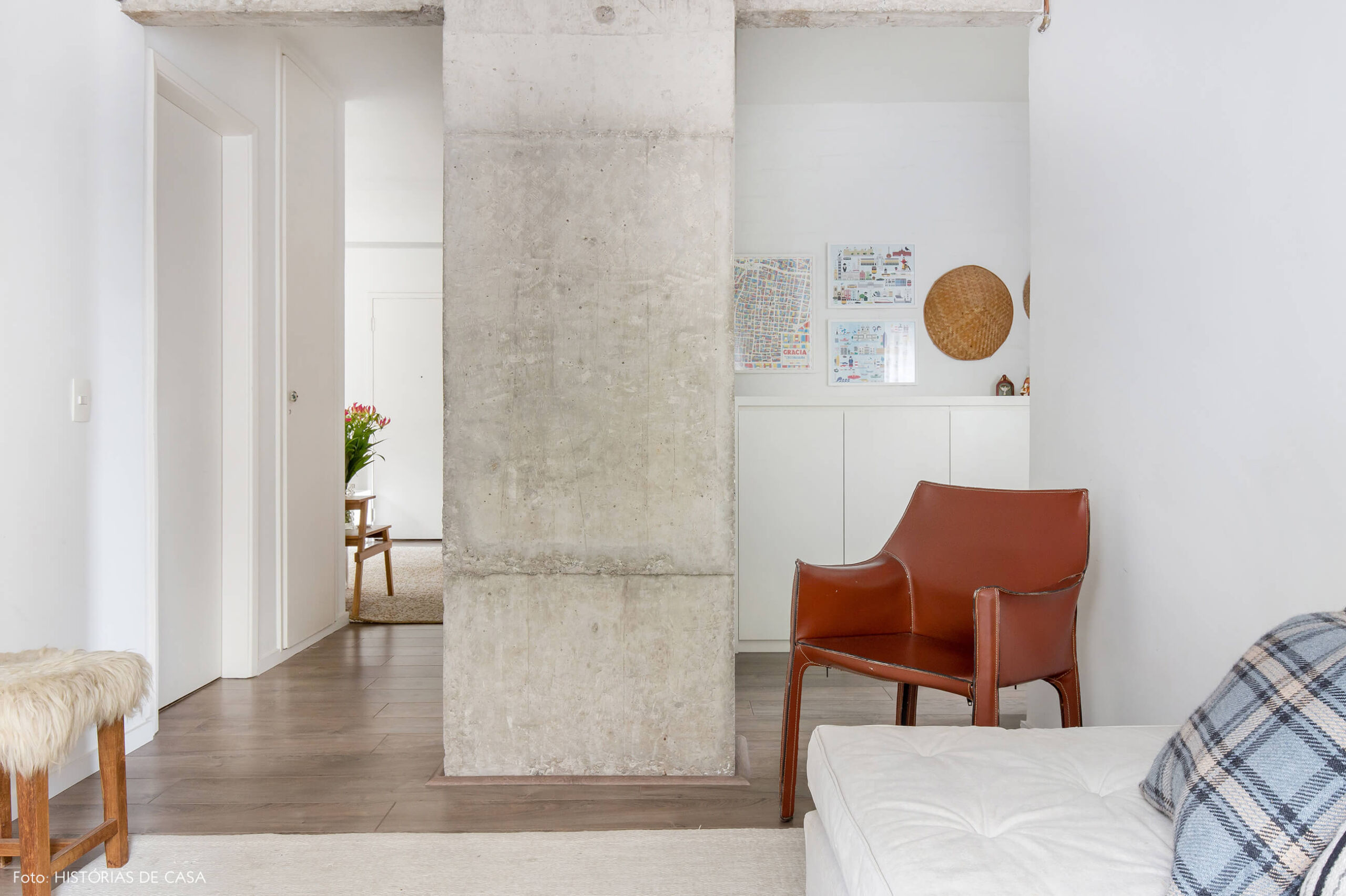 Sala aconchegante com pilar de concreto e poltrona de couro