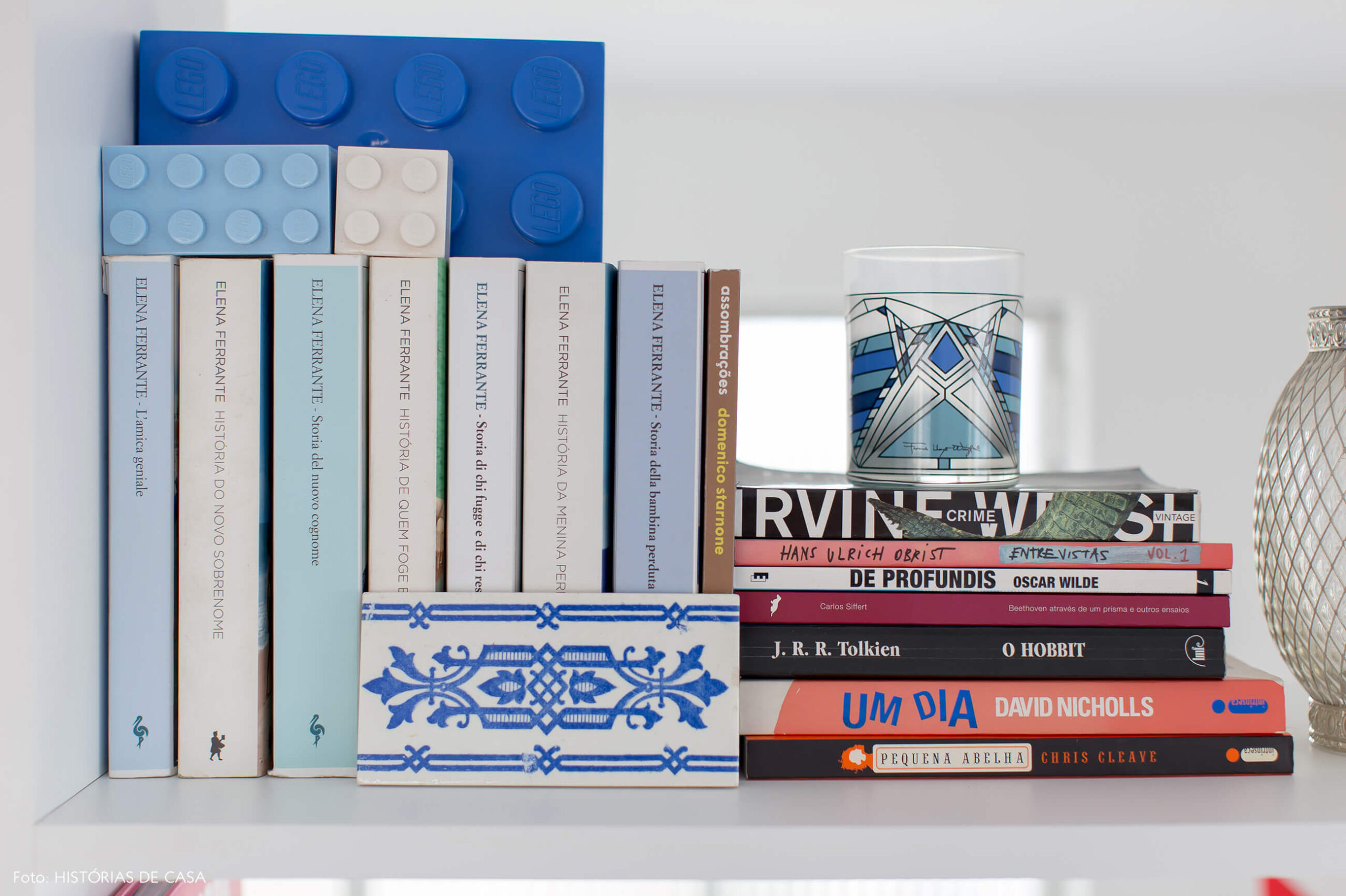 Home office com estante branca e livros separados por cor