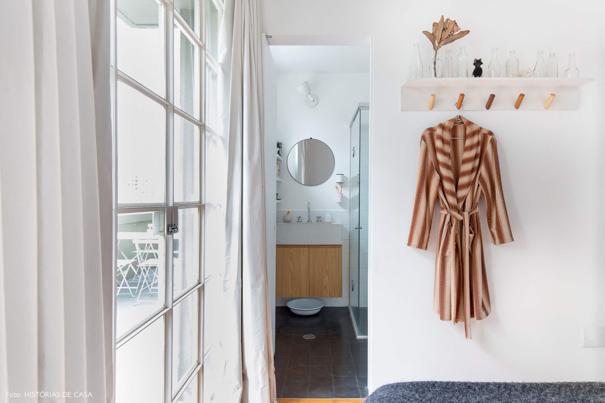 Quarto com cabideiro de madeira e banheiro de estilo industrial