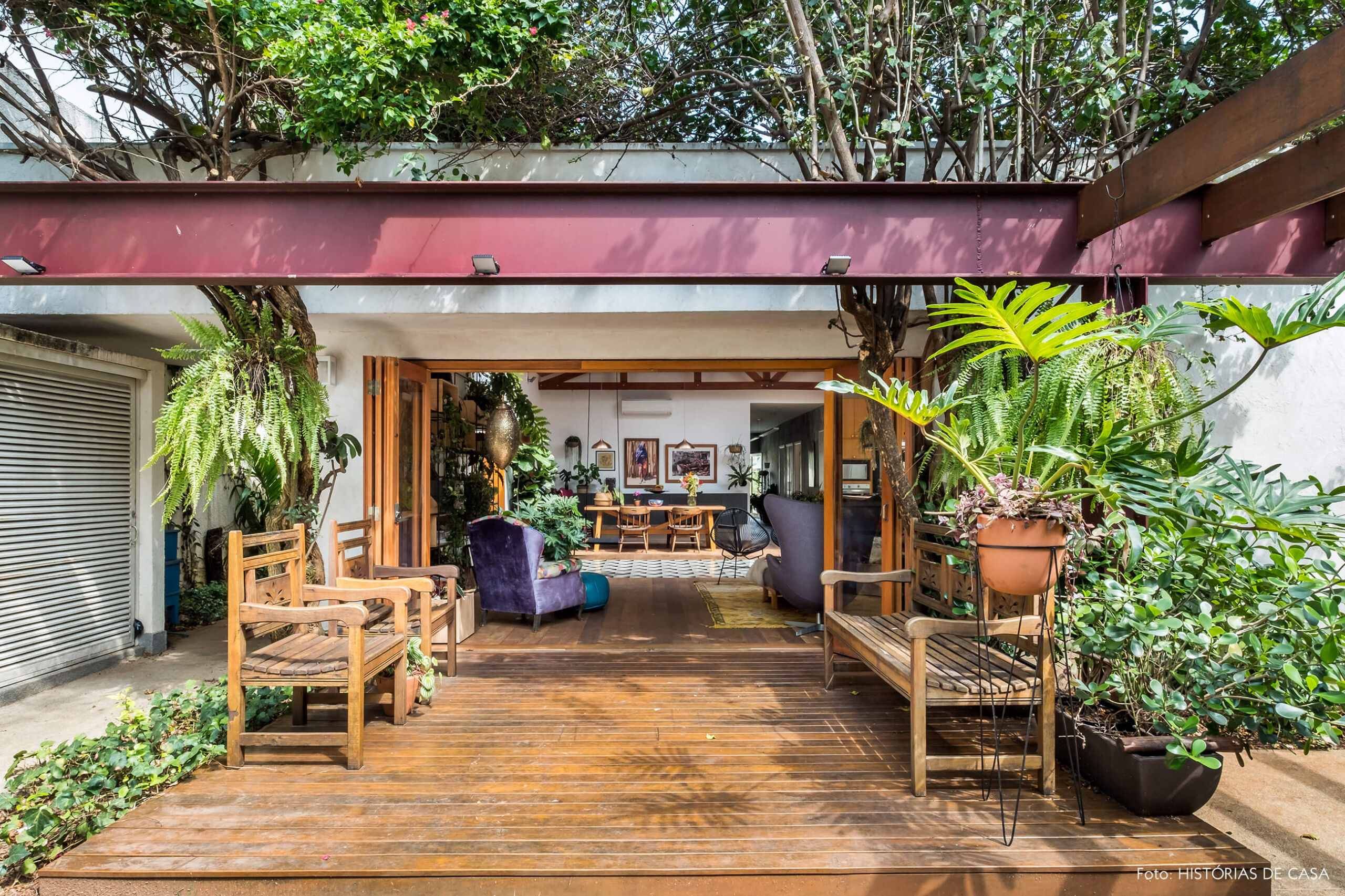 Casa com jardim. Deck de madeira na entrada e sala integrada.