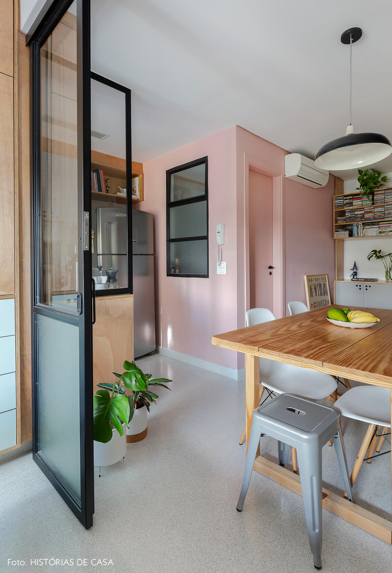 Apartamento pequeno com parede colorida, piso claro e divisórias de vidro