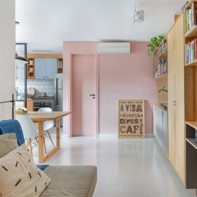 Apartamento pequeno com tons claros e parede rosa, ambientes integrados