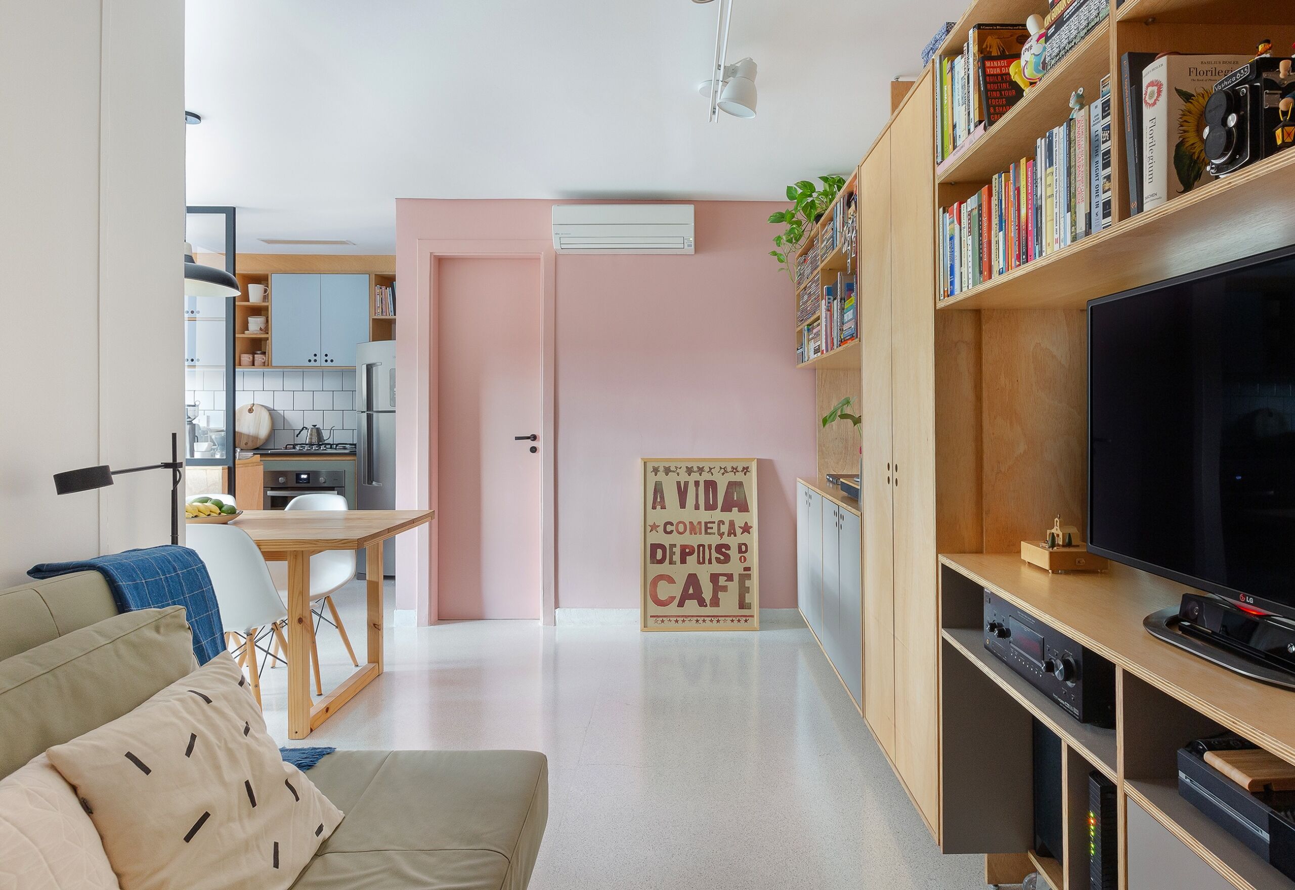 Apartamento pequeno com tons claros e parede rosa, ambientes integrados