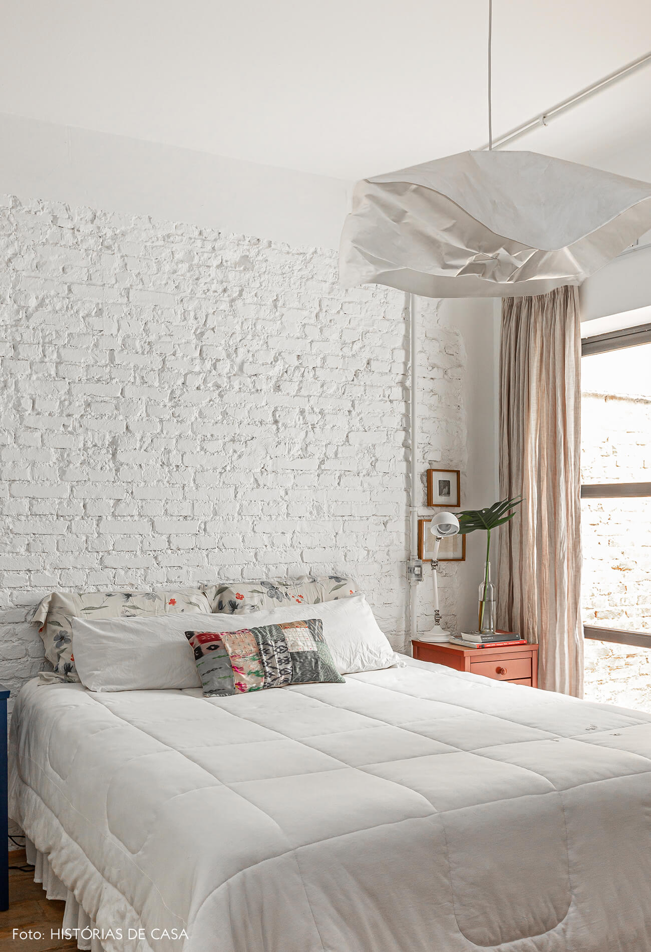 Apartamento térreo, quarto com parede de tijolinho branco e vista para o jardim
