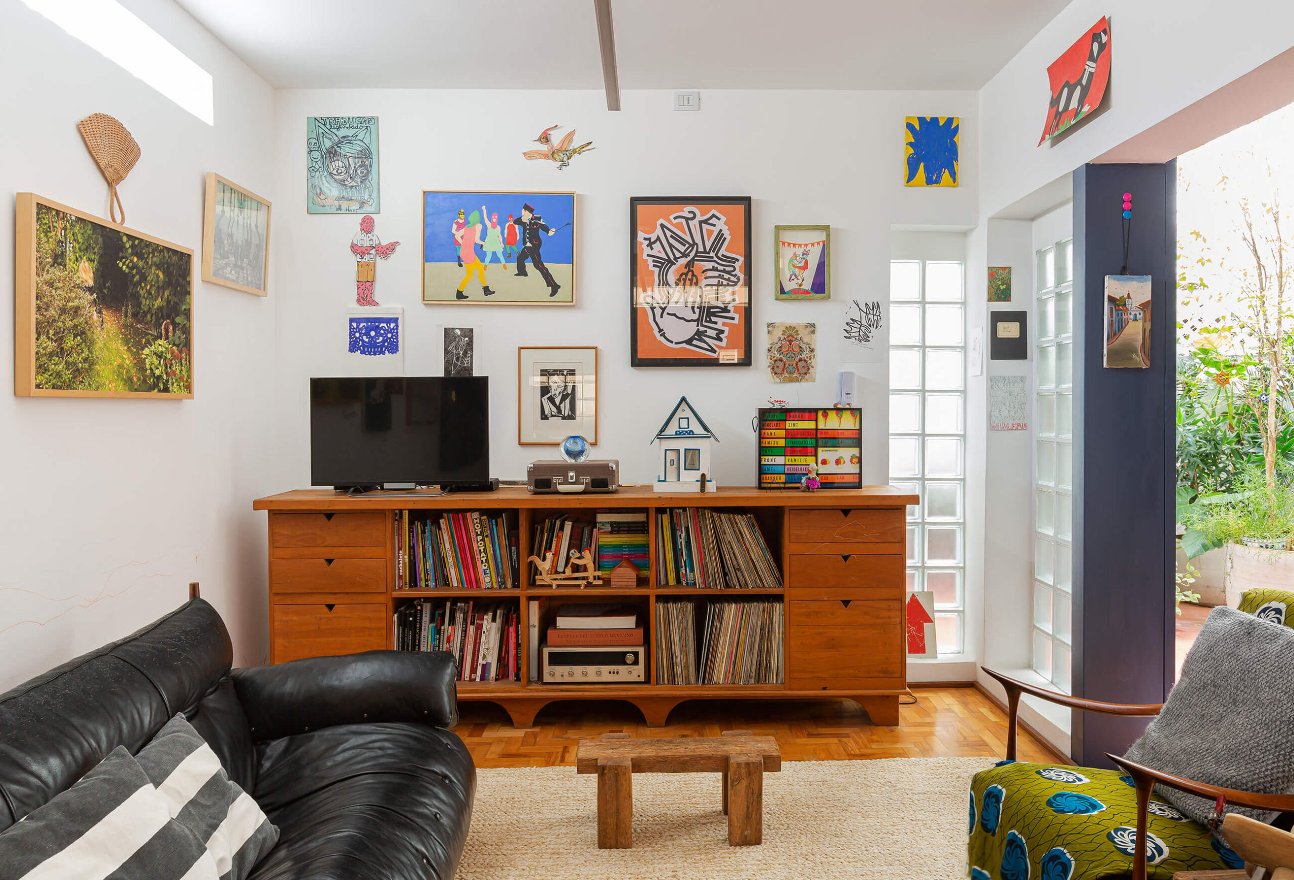 Apartamento reformado, sala com parede de quadros e detalhes coloridos