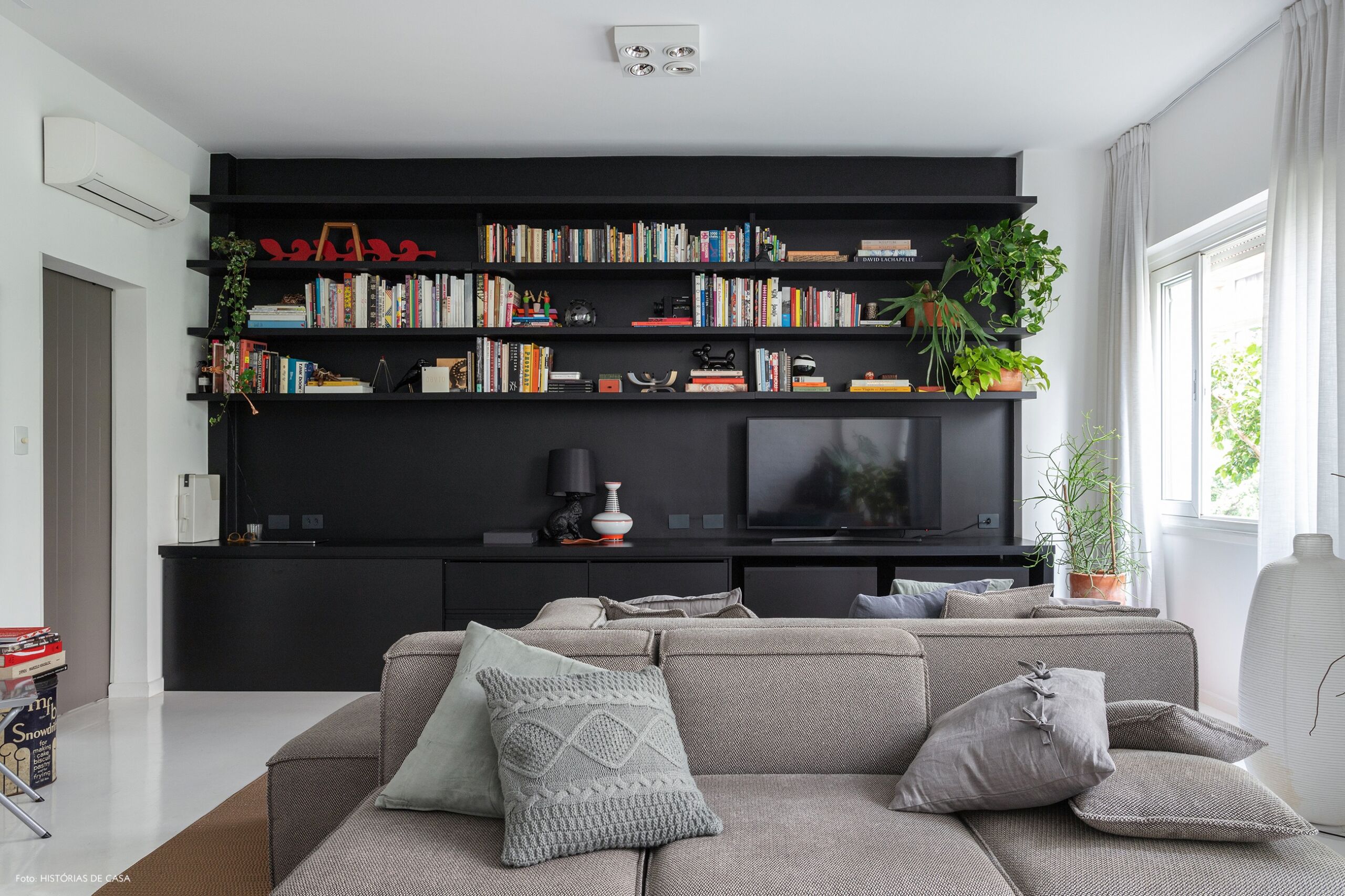 Apartamento escandinavo, sala com estante preta e sofá cinza